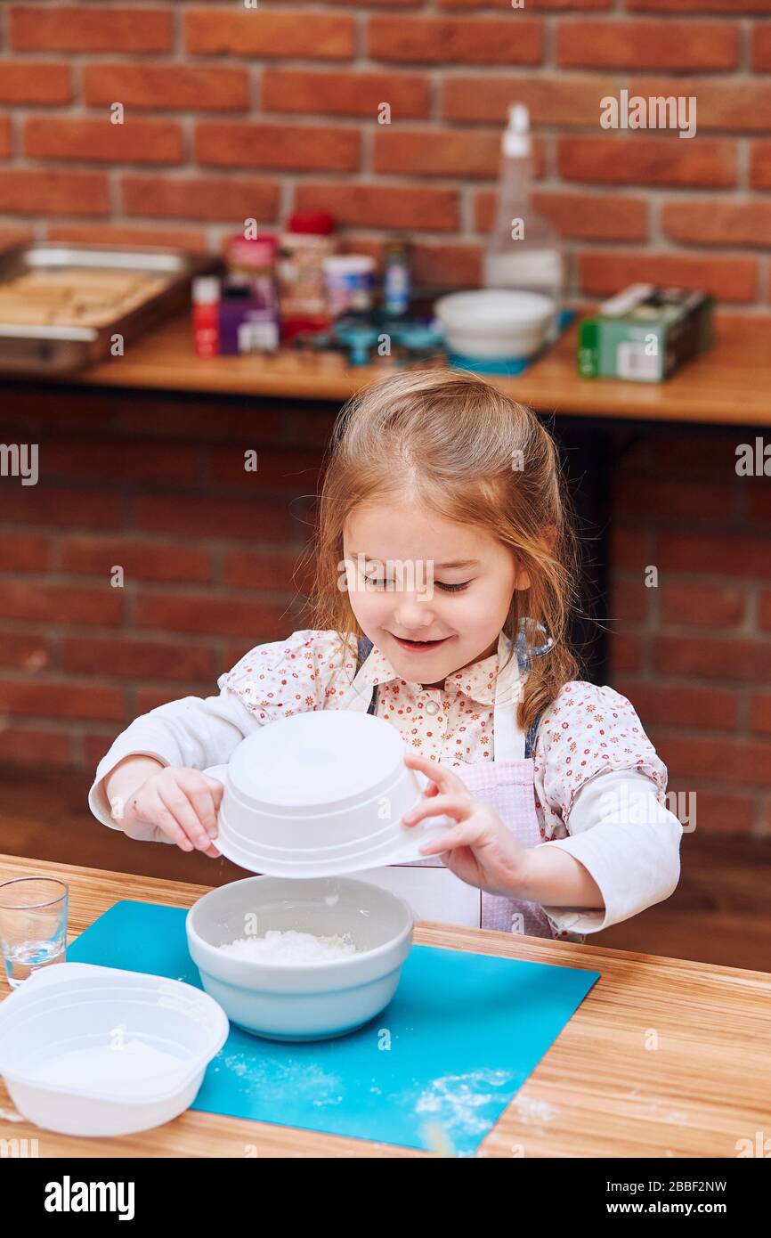 Little girl combining the ingredients for baking the cake. Kid taking