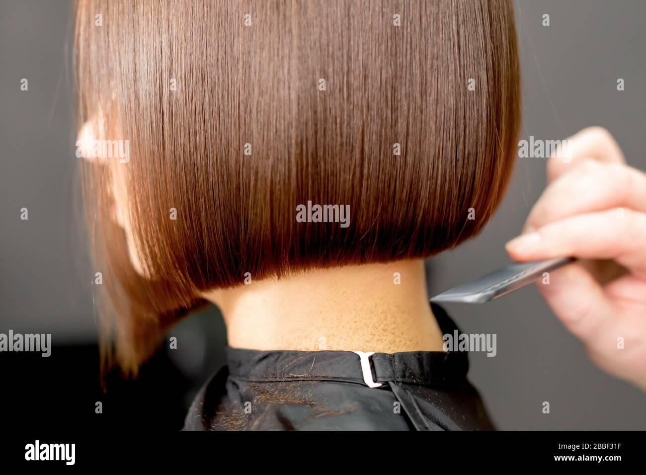 Hairdresser combs short hair of woman close up in hair salon