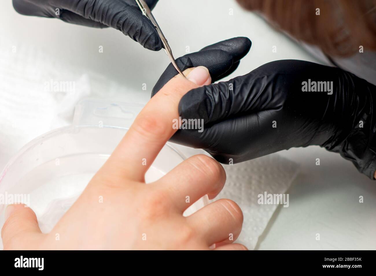 Beautician cutting cuticles of female nails during manicure procedure