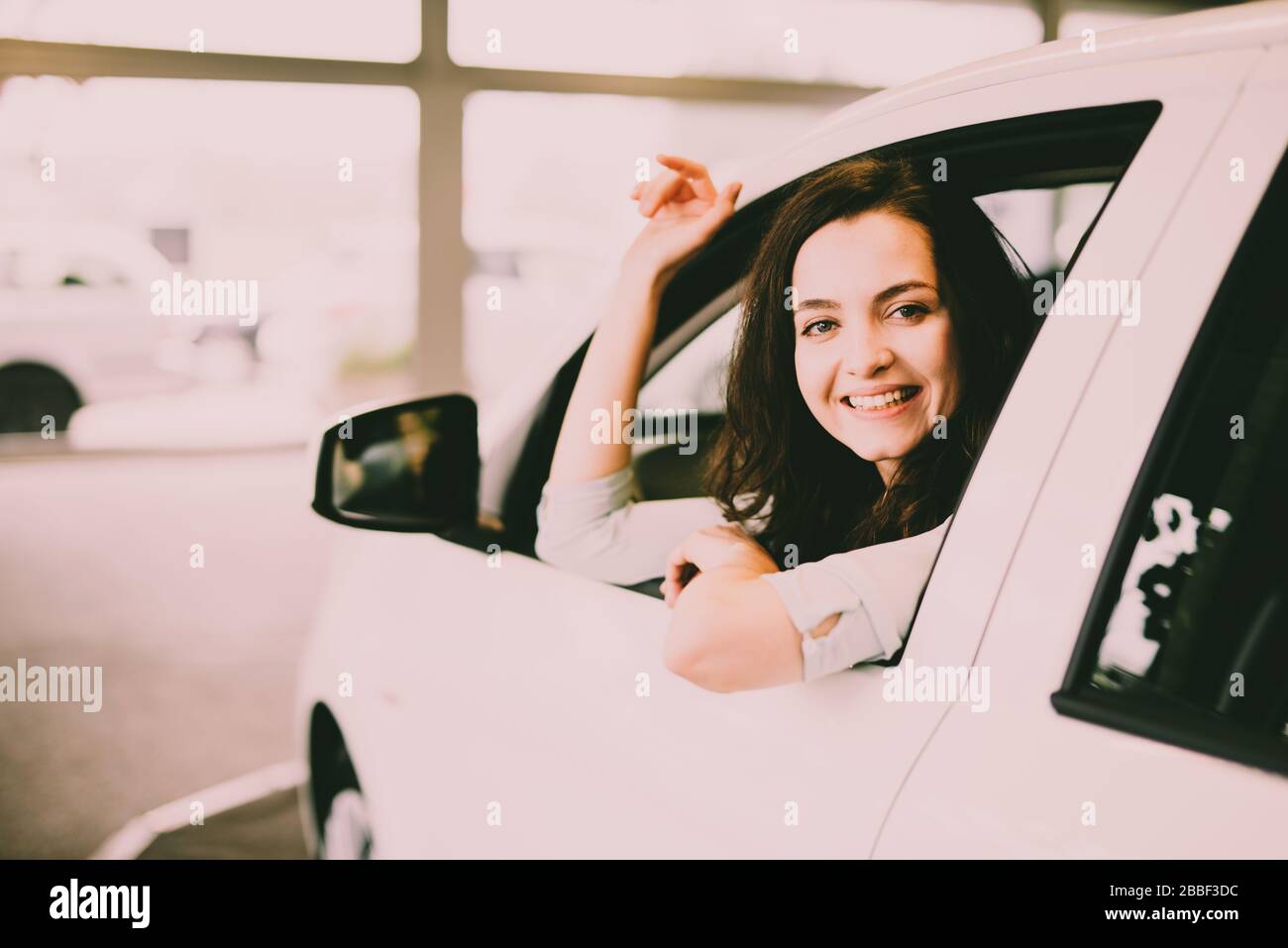 Cheerful Laughing Young Woman Sitting In A New Car In A Car Dealership cheerful-laughing-young-woman-sitting-in-a-new-car-in-a-car-dealership
