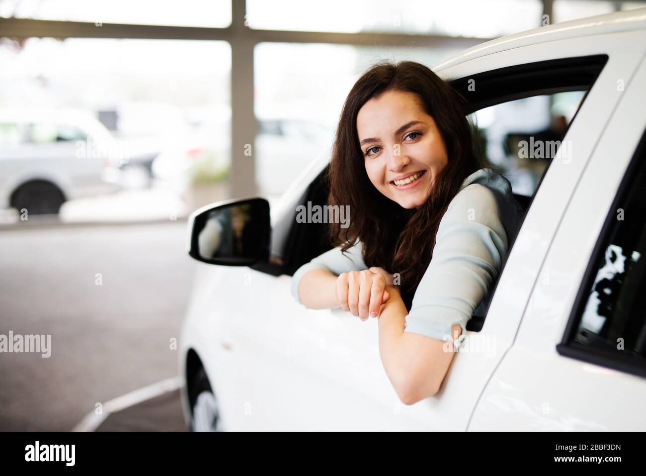Cheerful Laughing Young Woman Sitting In A New Car In A Car Dealership cheerful-laughing-young-woman-sitting-in-a-new-car-in-a-car-dealership