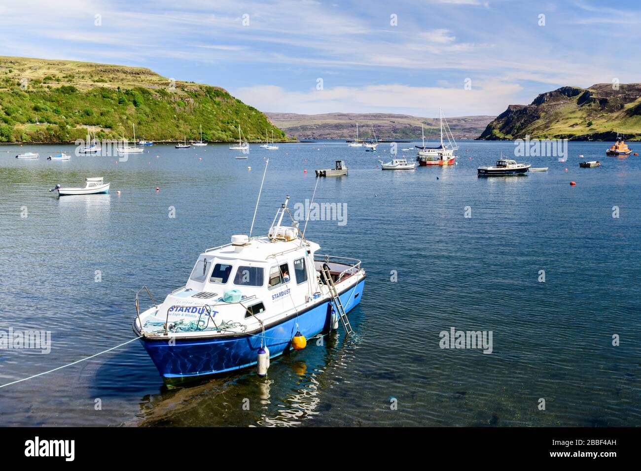 A boat is anchored in the harbour at Portree on the Isle of Skye in Scotland Stock Photo