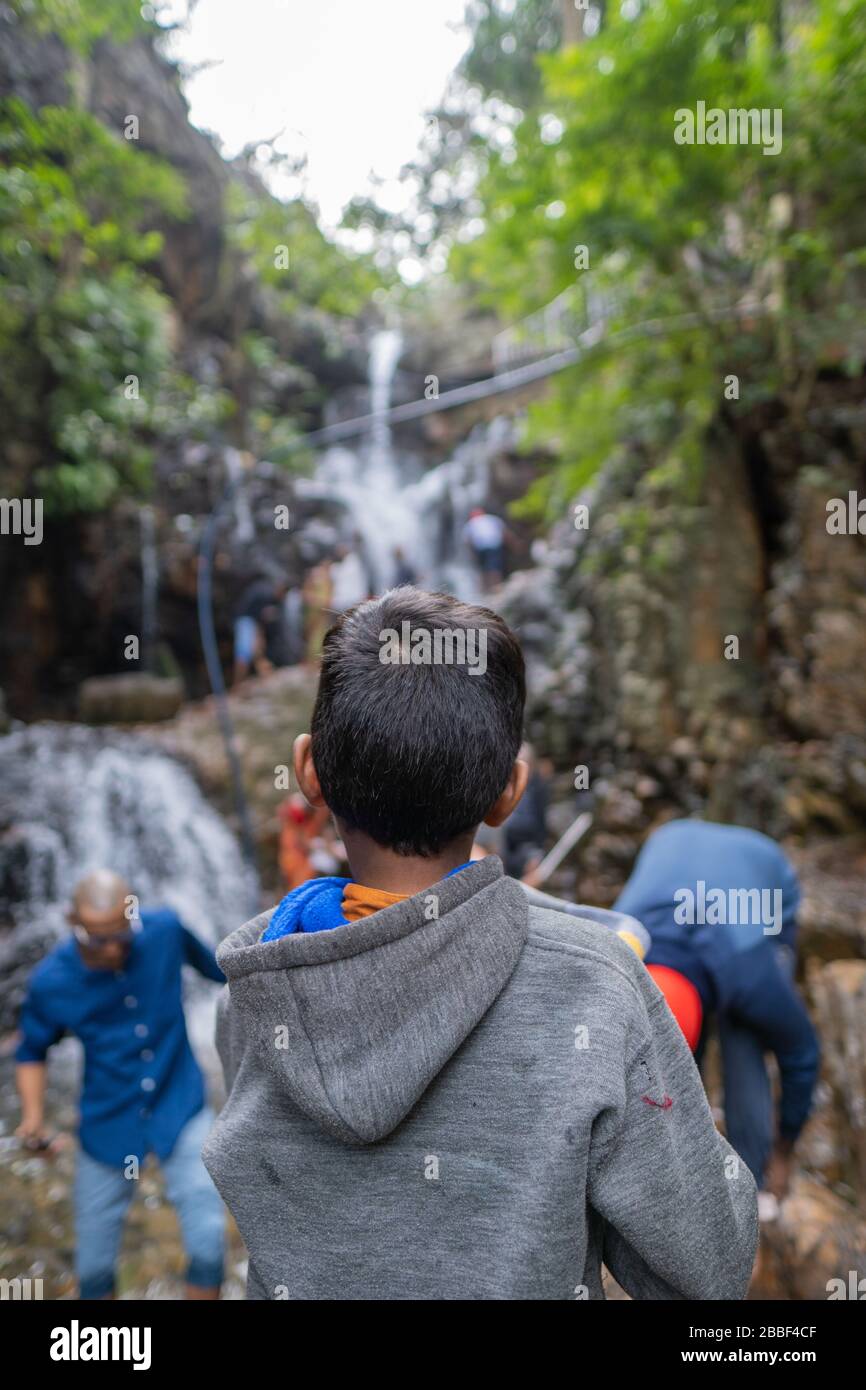 Small kid looking up towards the Waterfalls Stock Photo