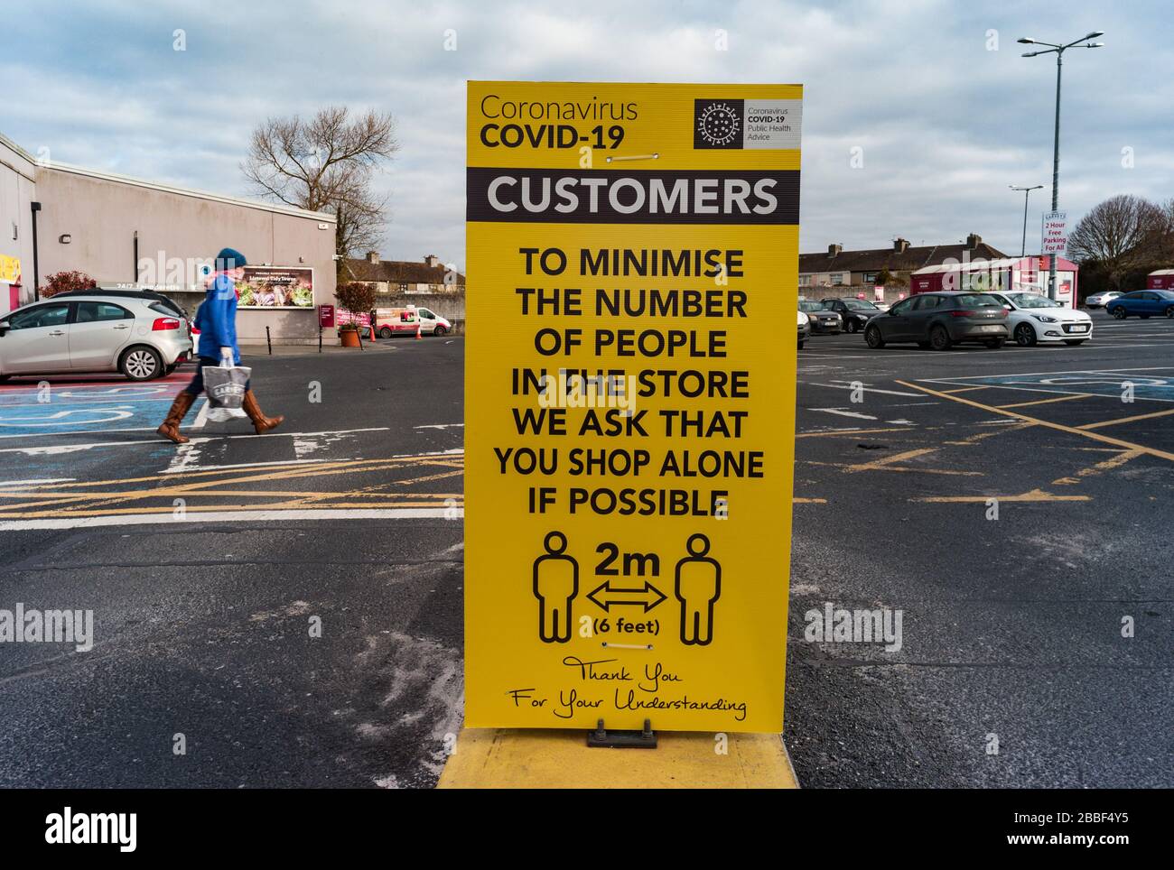 Listowel, Ireland - 30th March 2020:  Covid-19 Sign at entrance to supermarket car park warning customers of social distancing rules of 2 meters Stock Photo