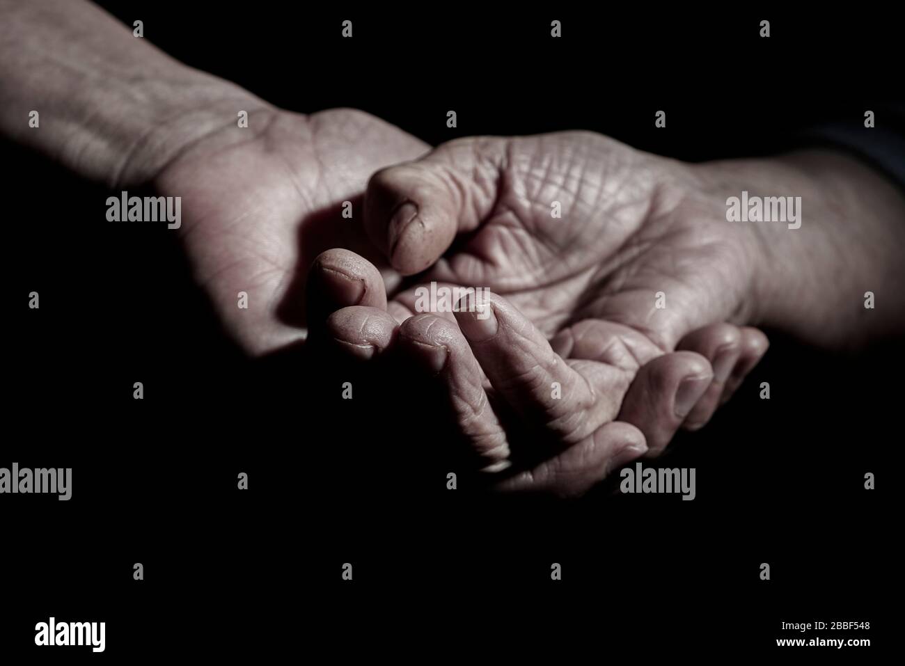 closeup of a young caucasian man holding the hand of a senior caucasian woman Stock Photo