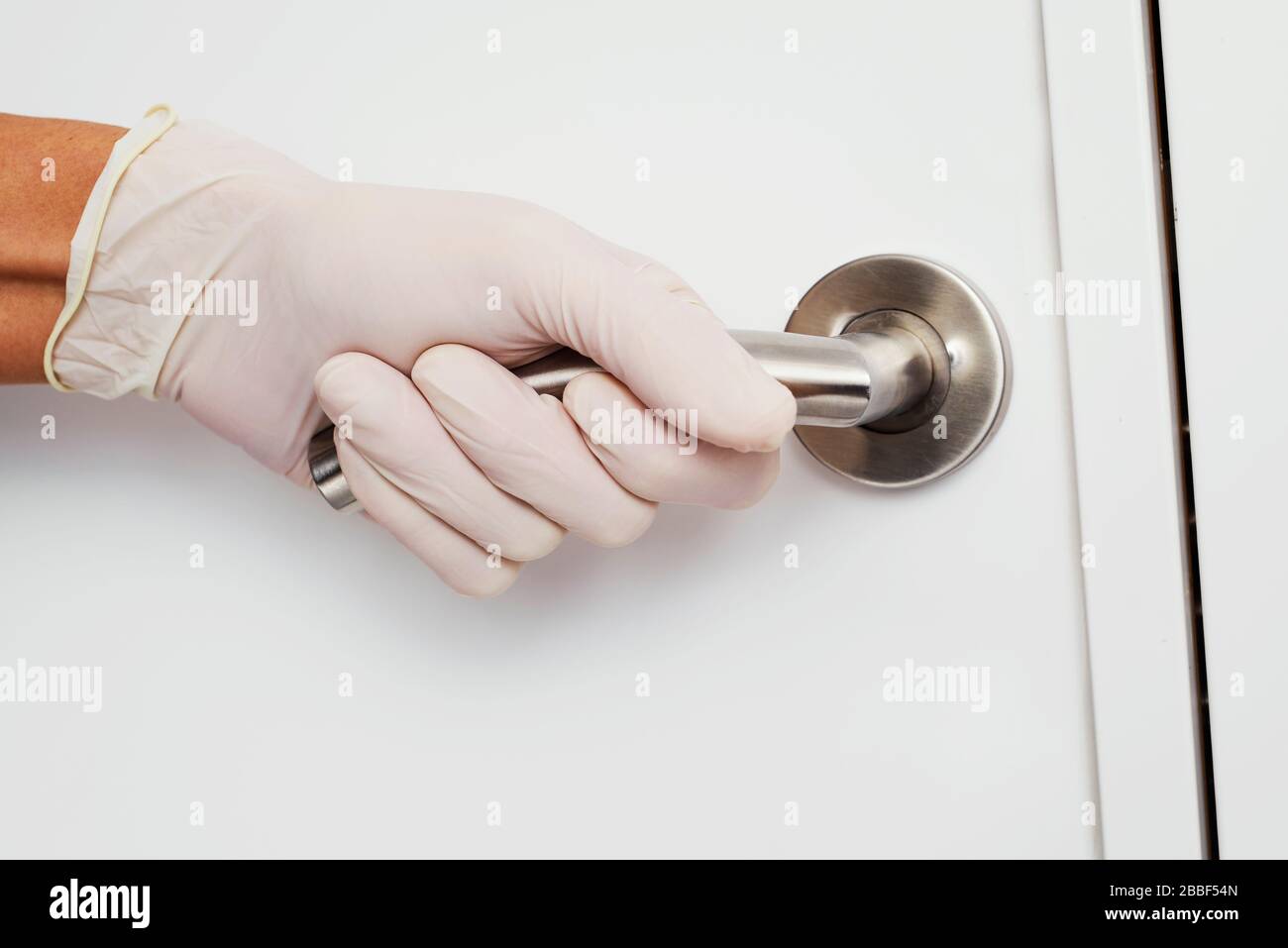 closeup of a caucasian man opening a door wearing latex gloves, as a