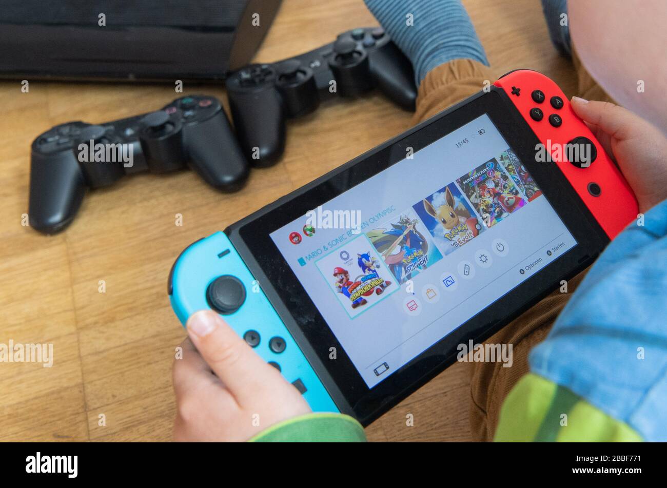 31 March 2020, Lower Saxony, Hanover: ILLUSTRATION - A child is playing with a Nintendo Switch game console while a Sony Playstation 3 with two controllers is seen in the background (scene posed) Because of the contact restrictions in the Corona crisis, criminologist Christian Pfeiffer sees a significantly increased risk of video and computer game addiction among children and adolescents. Photo: Julian Stratenschulte/dpa Stock Photo