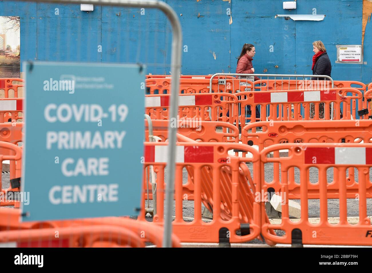 People walk past coronavirus signs at the Covid-19 Centre at Altnagelvin Hospital, Londonderry, as the UK continues in lockdown to help curb the spread of the coronavirus. Stock Photo