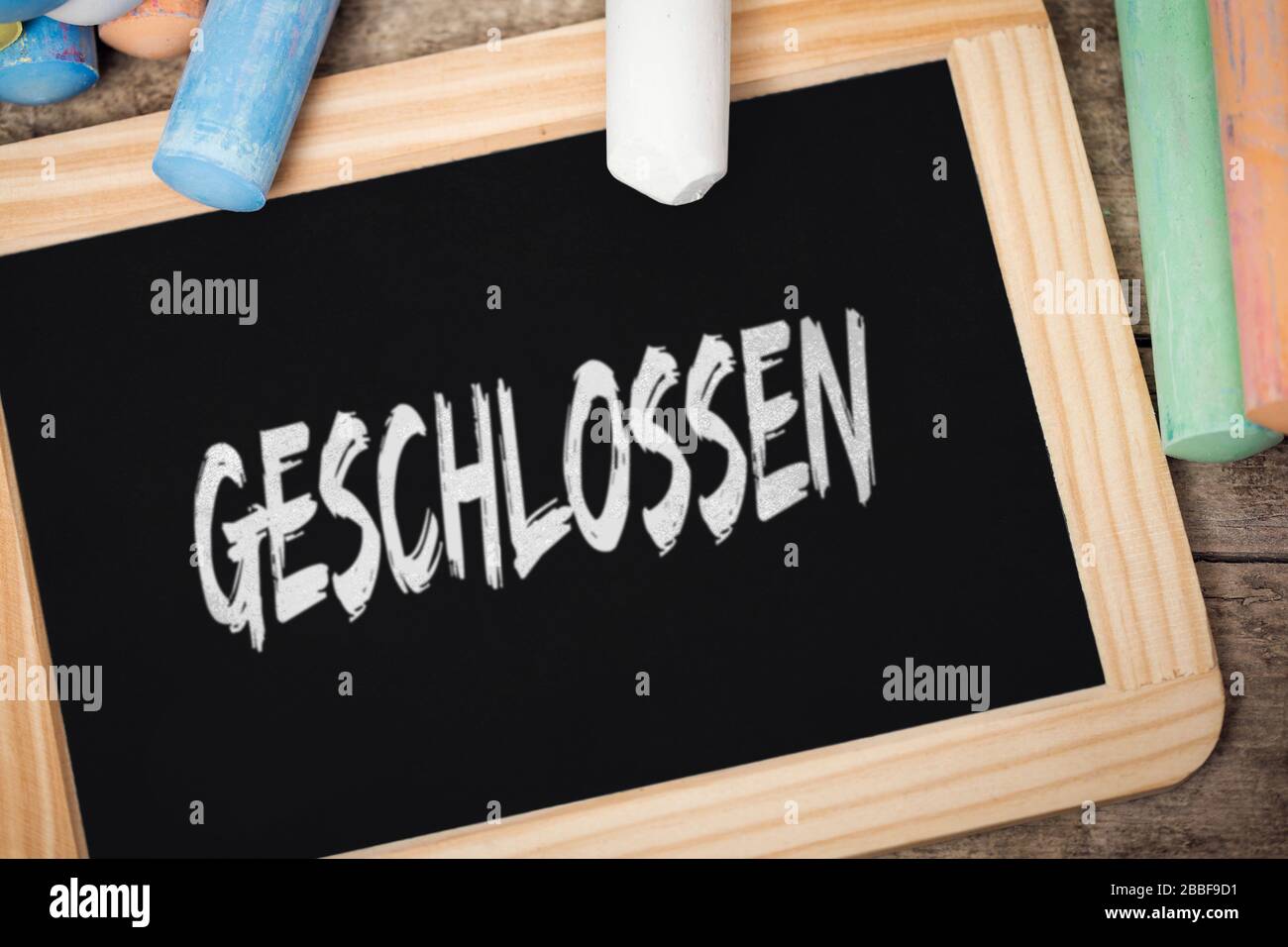 Blackboard with german word geschlossen, which means closed, concept corona or covid-19 virus, kindergarten, nursery and school, pandemic provisions Stock Photo