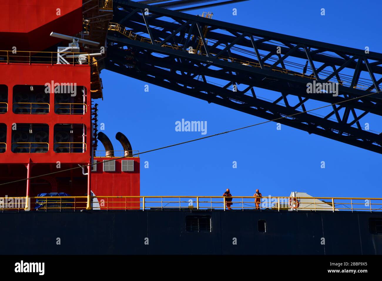 Rotterdam, The Netherlands-March 2020: Close up of two man standing on docked offshore platform, largest crane vessel in the world (Sleipnir) with pro Stock Photo
