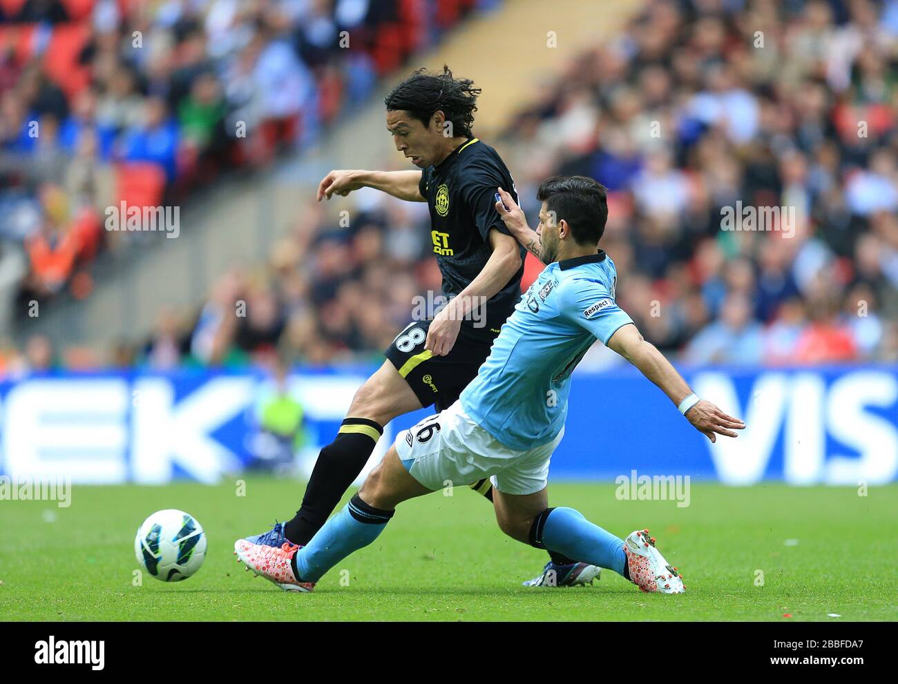 Wigan Athletic's Roger Espinoza (left) and Manchester City's Sergio Aguero (right) battle for the ball Stock Photo