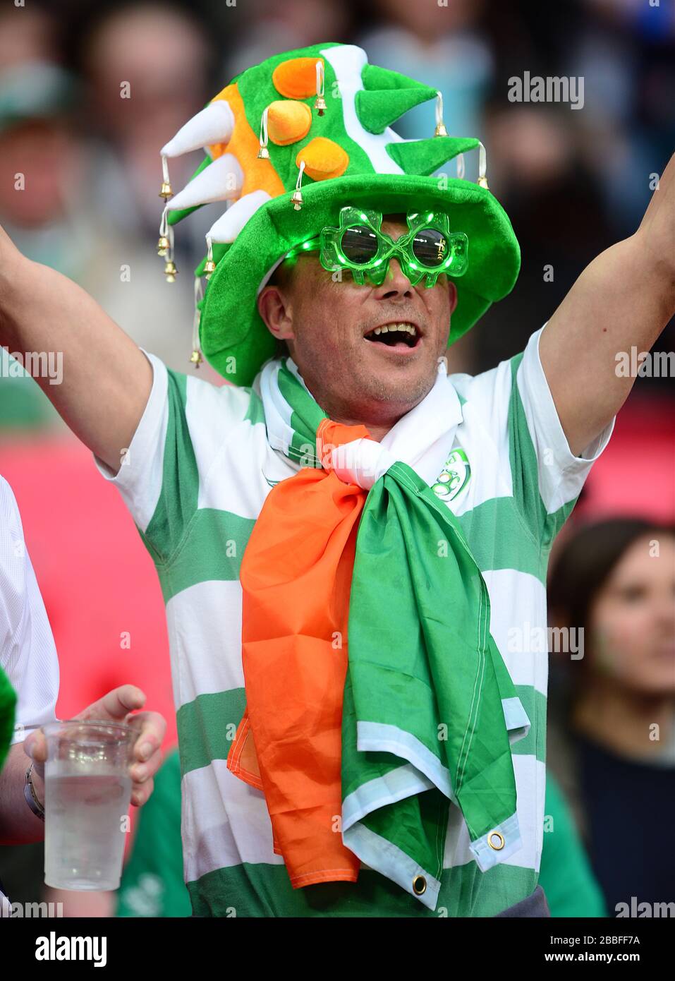 A Republic of Ireland fan wearing a jester hat and comedy glasses in the stands Stock Photo
