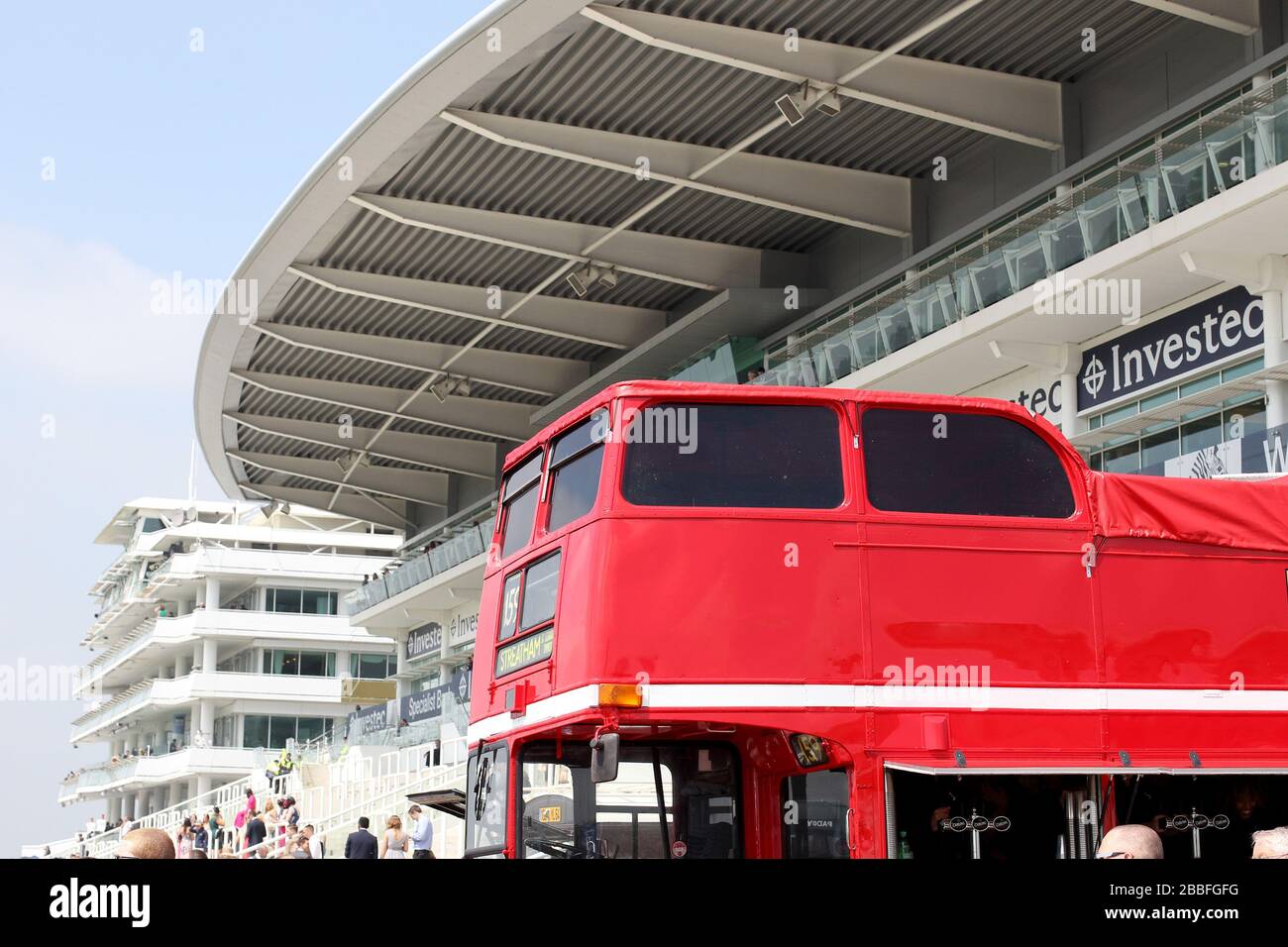 A red bus sits in front of the stands at Epsom Down Racecourse Stock Photo