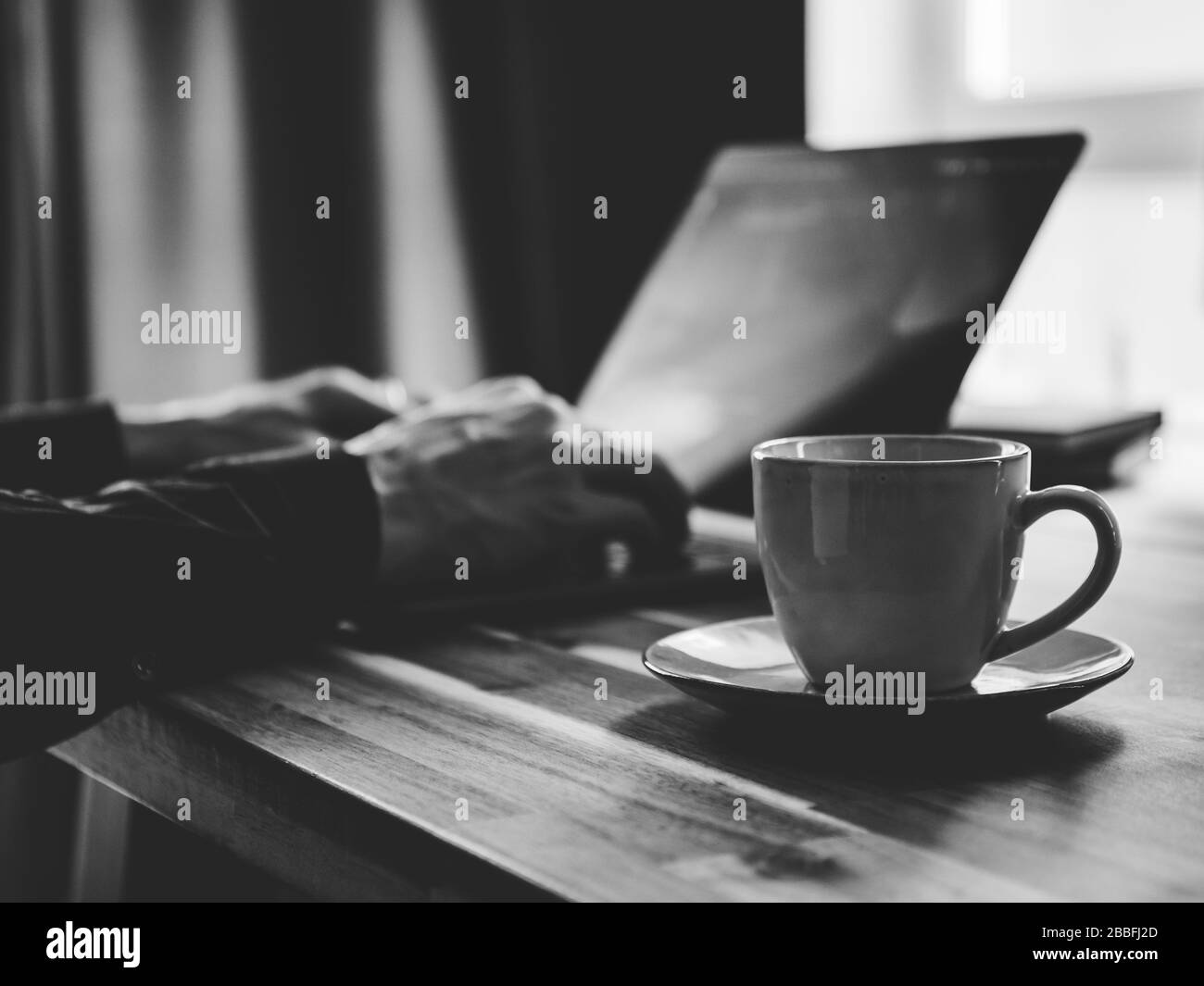 A man is typing on a laptop keyboard. Concept of work from home, black and white photo. Stock Photo