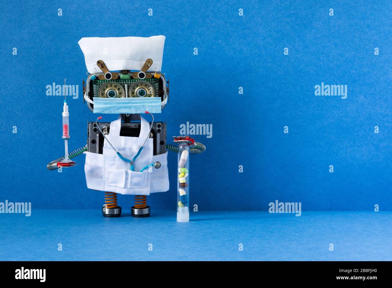Robot medic with surgical mask, stethoscope and syringe blood test on blue background. copy space Stock Photo