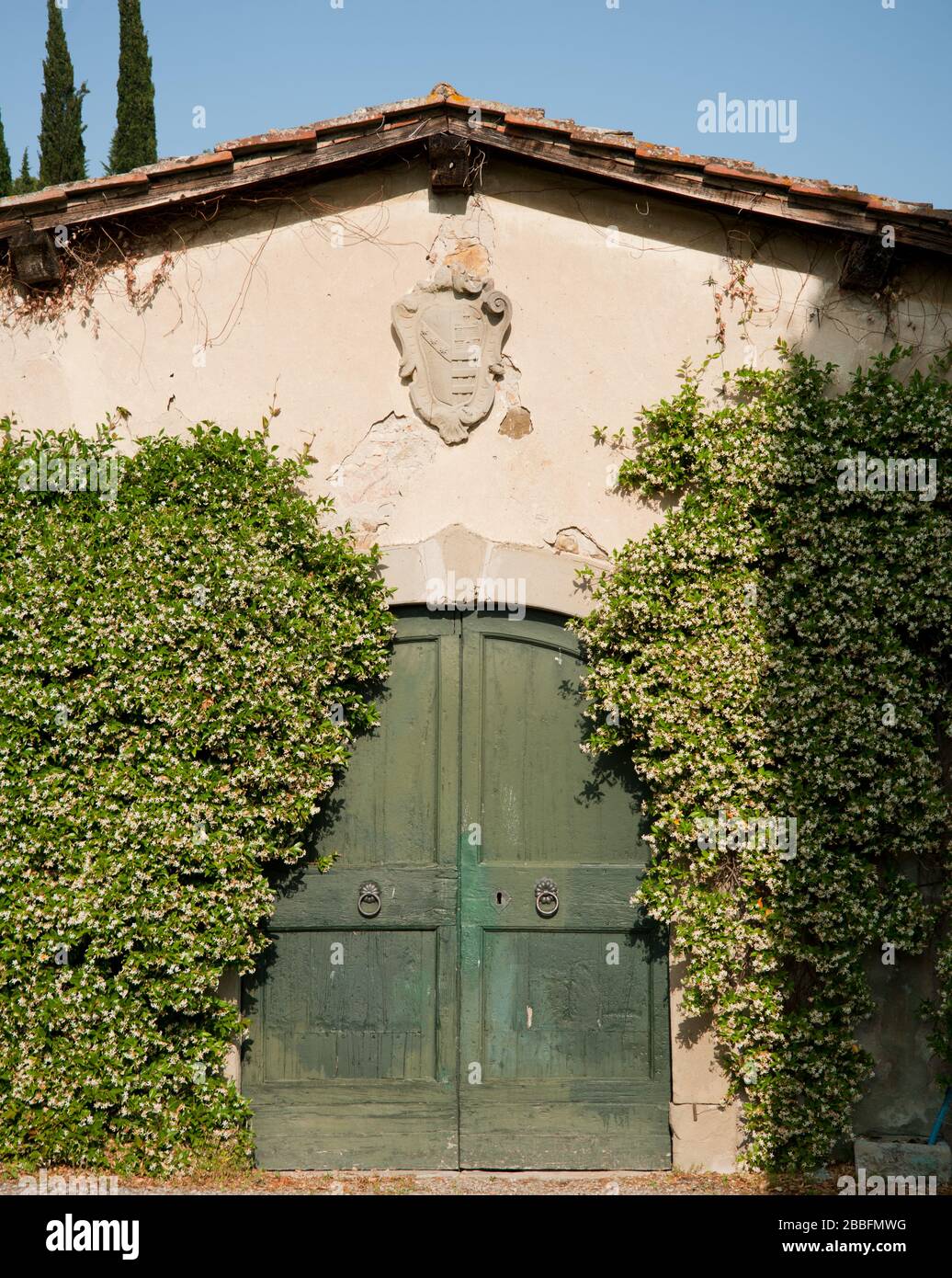shed with green double wing doors and coat of arms, Tuscany, Italy Stock Photo