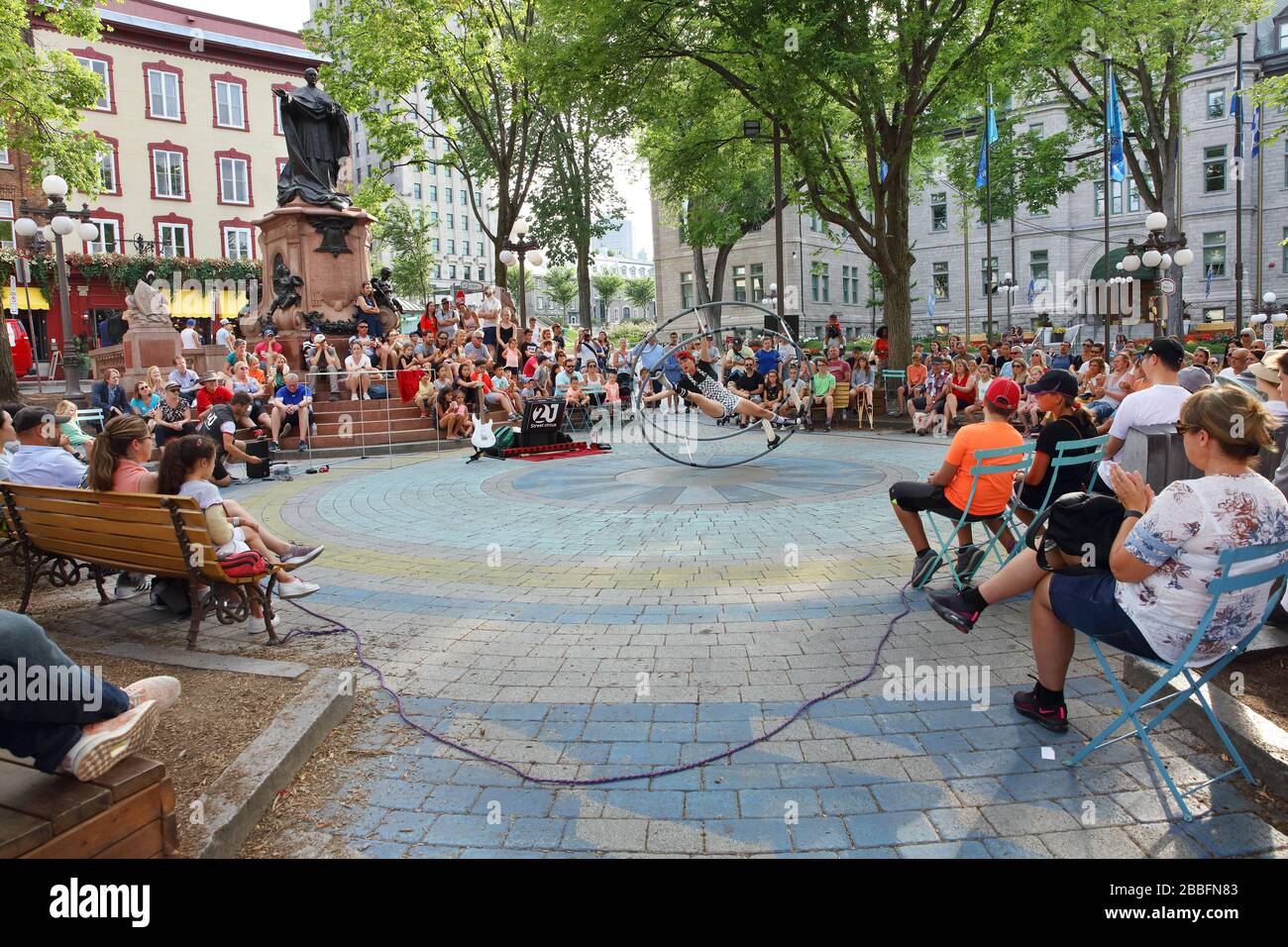 Crowd of people watching a woman on a German Wheel performing acrobatic tricks at Place de l'Hotel de Ville in Old Quebec City, Province of Quebec, Canada Stock Photo