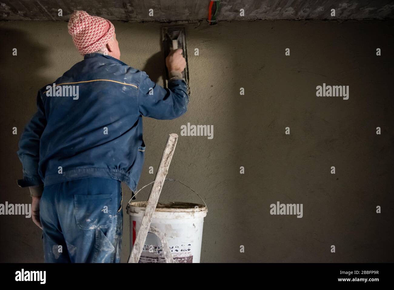 Construction worker plastering interior wall using cement plaster  Worker plastering the wall by concrete at the construction site Stock Photo