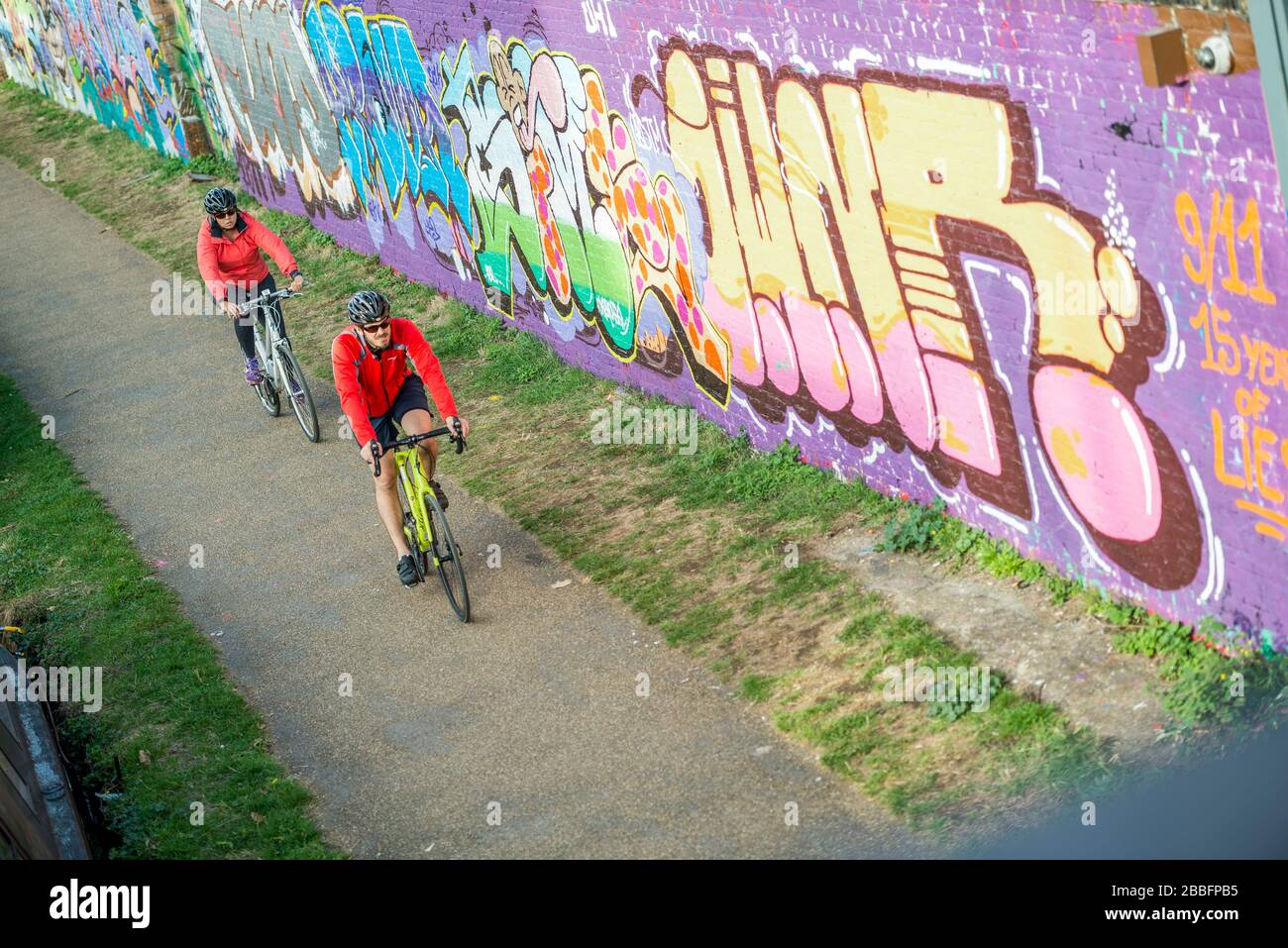 A couple ride bikes along the union canal cycle path in Hackney Wick