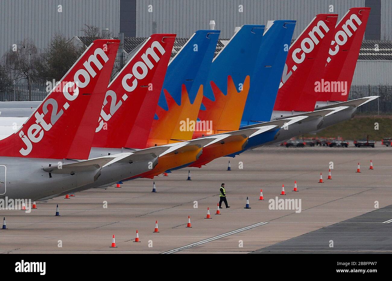 Birmingham, West Midlands, UK. 31st March 2020.  A worker walks under Jet2 aircraft parked on the tarmac at Birmingham Airport during the Coronavirus pandemic lockdown. Credit Darren Staples/Alamy Live News. Stock Photo