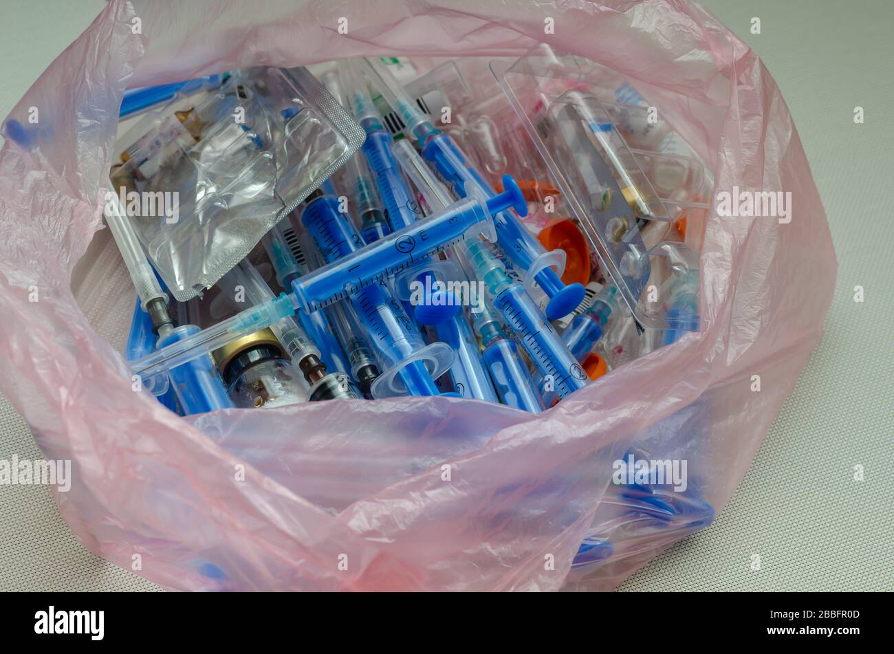 Used syringes, vials and ampoules in a bag. Cellophane bag with medical waste. Medical instruments for disposal. Close-up. Selective focus. Stock Photo