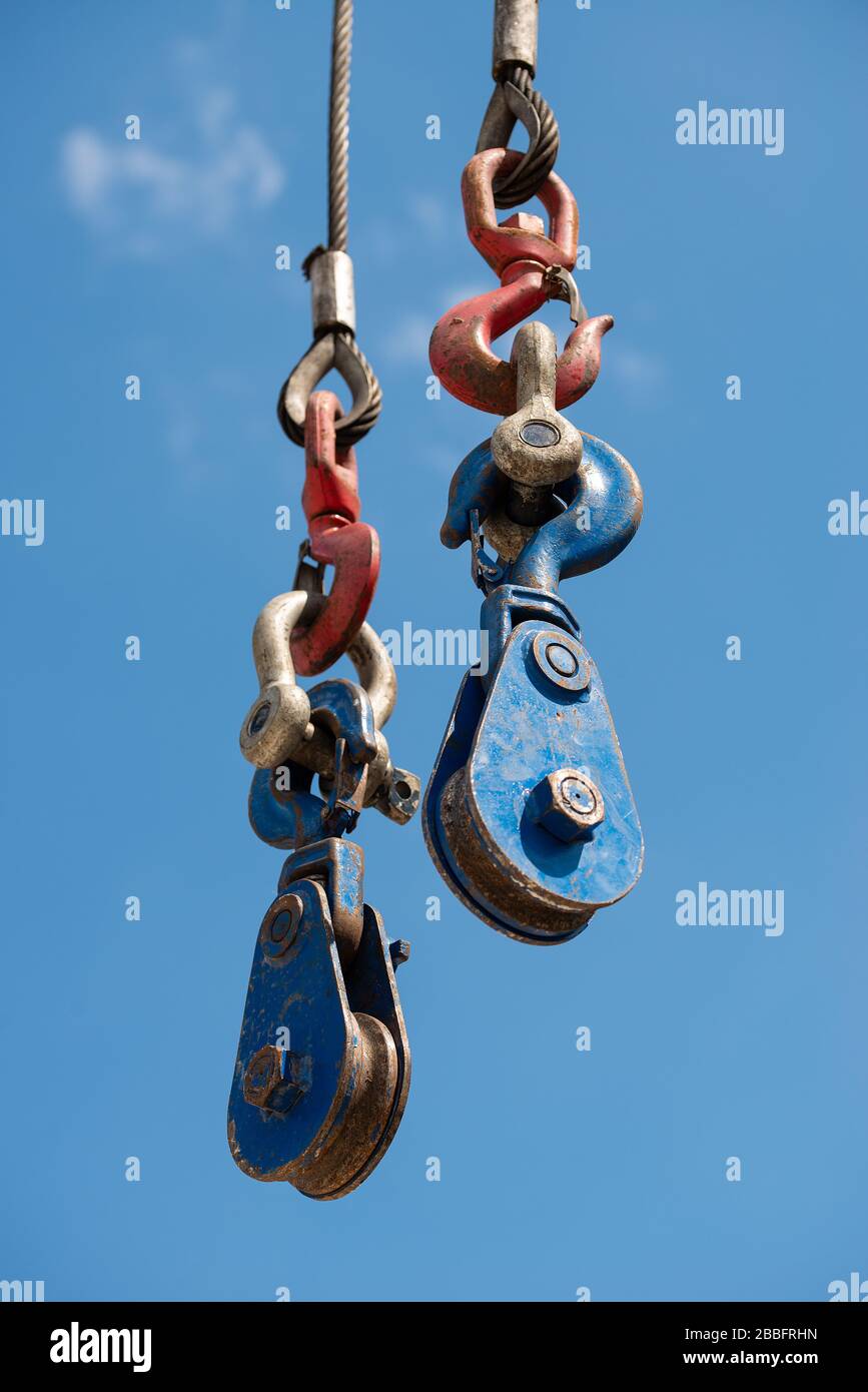 Low angle view of a construction site crane hook and pulley system against a clear blue sky. Stock Photo