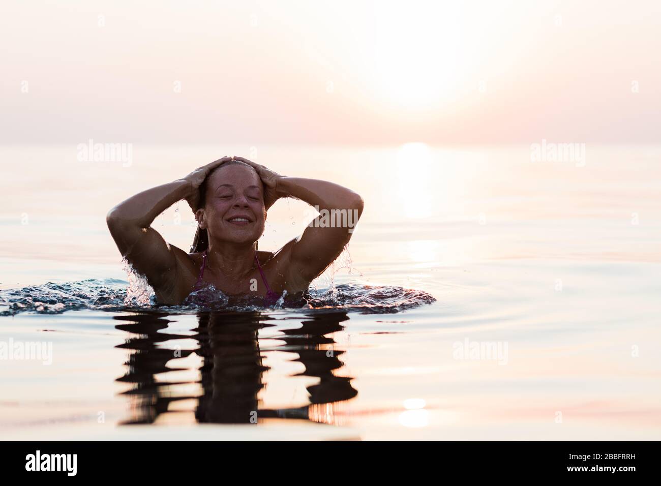 Young woman swimming in the sea in sunset Stock Photo