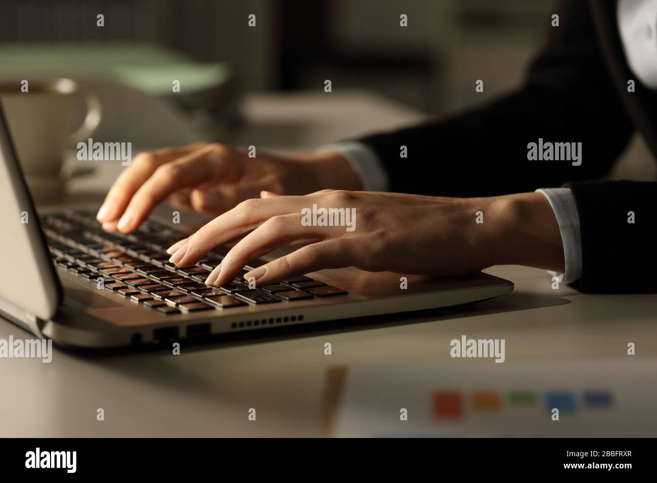 Close up of business woman hands typing on laptop at night in the office Stock Photo