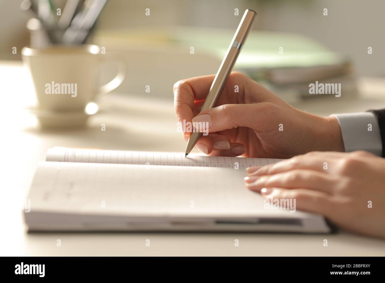 Close up of business woman hands writing notes on agenda at night in the office Stock Photo