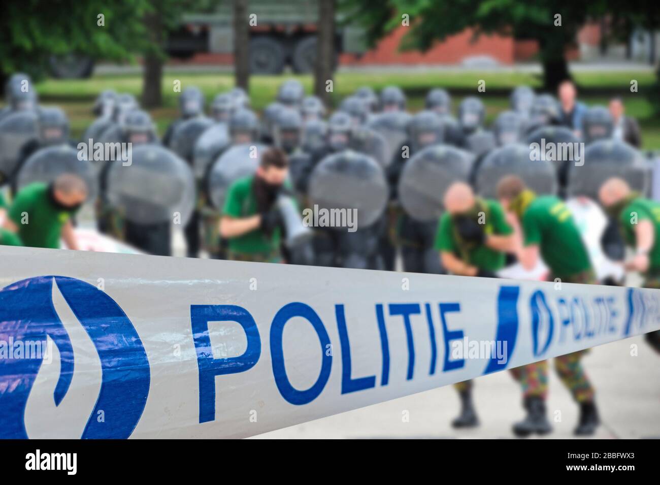 Politie / police tape in front of protesters and Belgian riot squad forming a protective barrier with riot shields Stock Photo