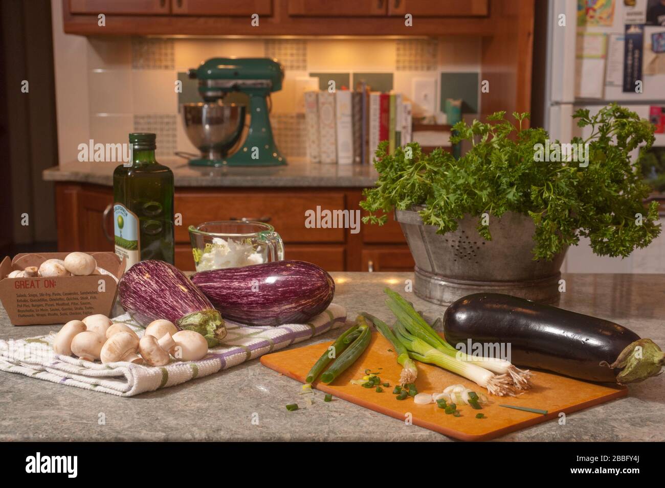 Eggplants, mushrooms, scallions,oil & spaces on kitchen counter. Food prep for making baba ganoush. Stock Photo