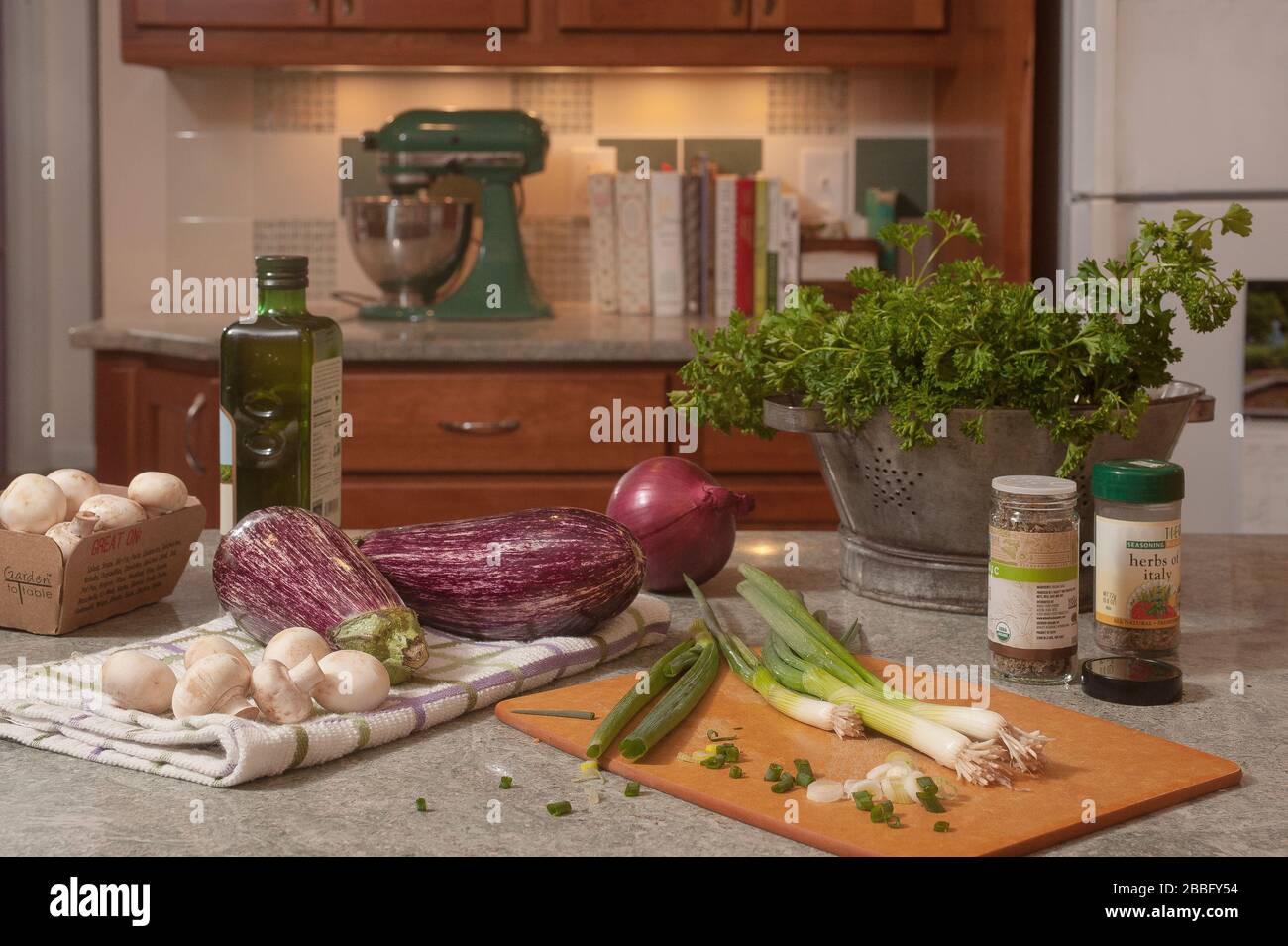 Eggplants, mushrooms, scallions,oil & spaces on kitchen counter. Food prep for making baba ganoush. Stock Photo
