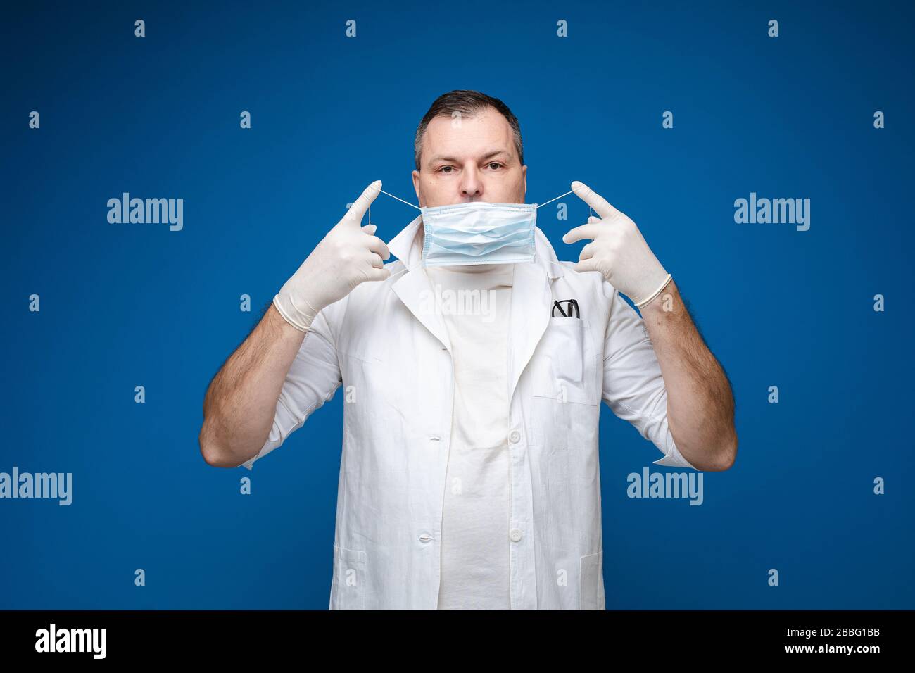 A strong man with glasses, white medical gown and mask stands, picture ...