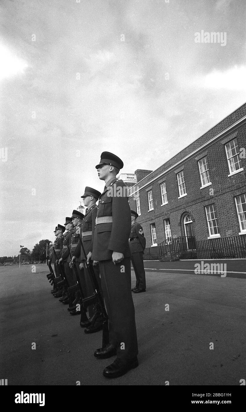 1968, a group of uniformed British soliders standing outside on the parade ground at a military parade at the Royal Artillery Barracks, Woolwich, South London, England, UK. Constructed between 1776 and 1802, the barracks has the largest parade ground in Britain. Stock Photo
