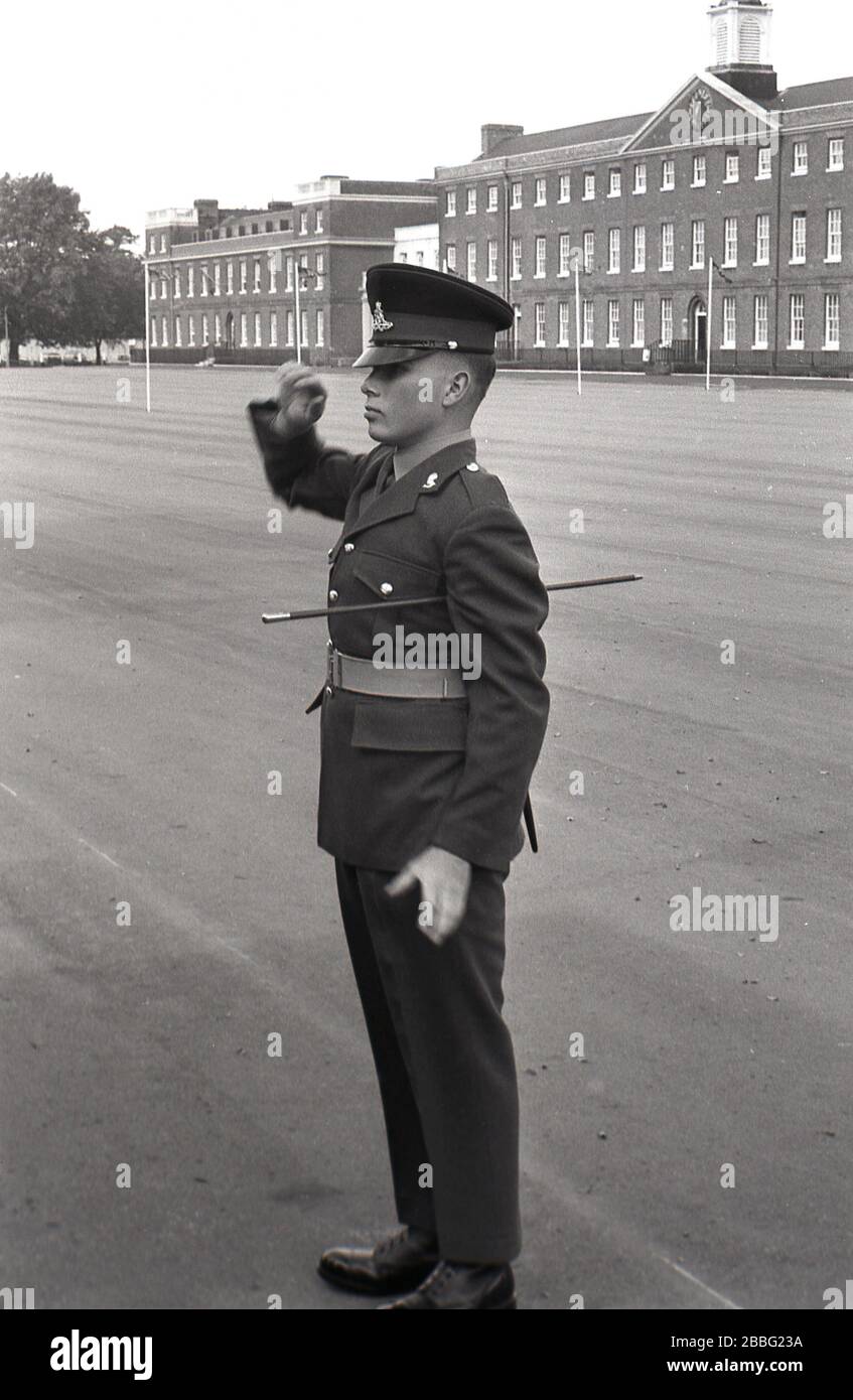 1968, a uniformed British solider standing outside on the parade ground saluting at a military parade at the Royal Artillery Barracks, Woolwich, South London, England, UK. Constructed between 1776 and 1802, the barracks has the largest parade ground in Britain. Stock Photo