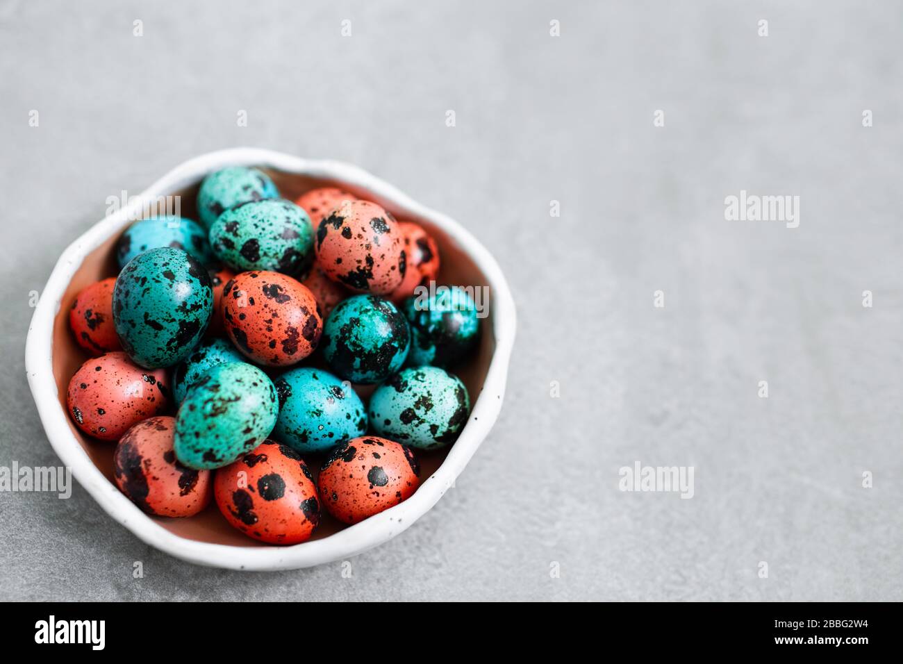 Painted red and blue quail eggs for Easter in small ceramic plate on ...