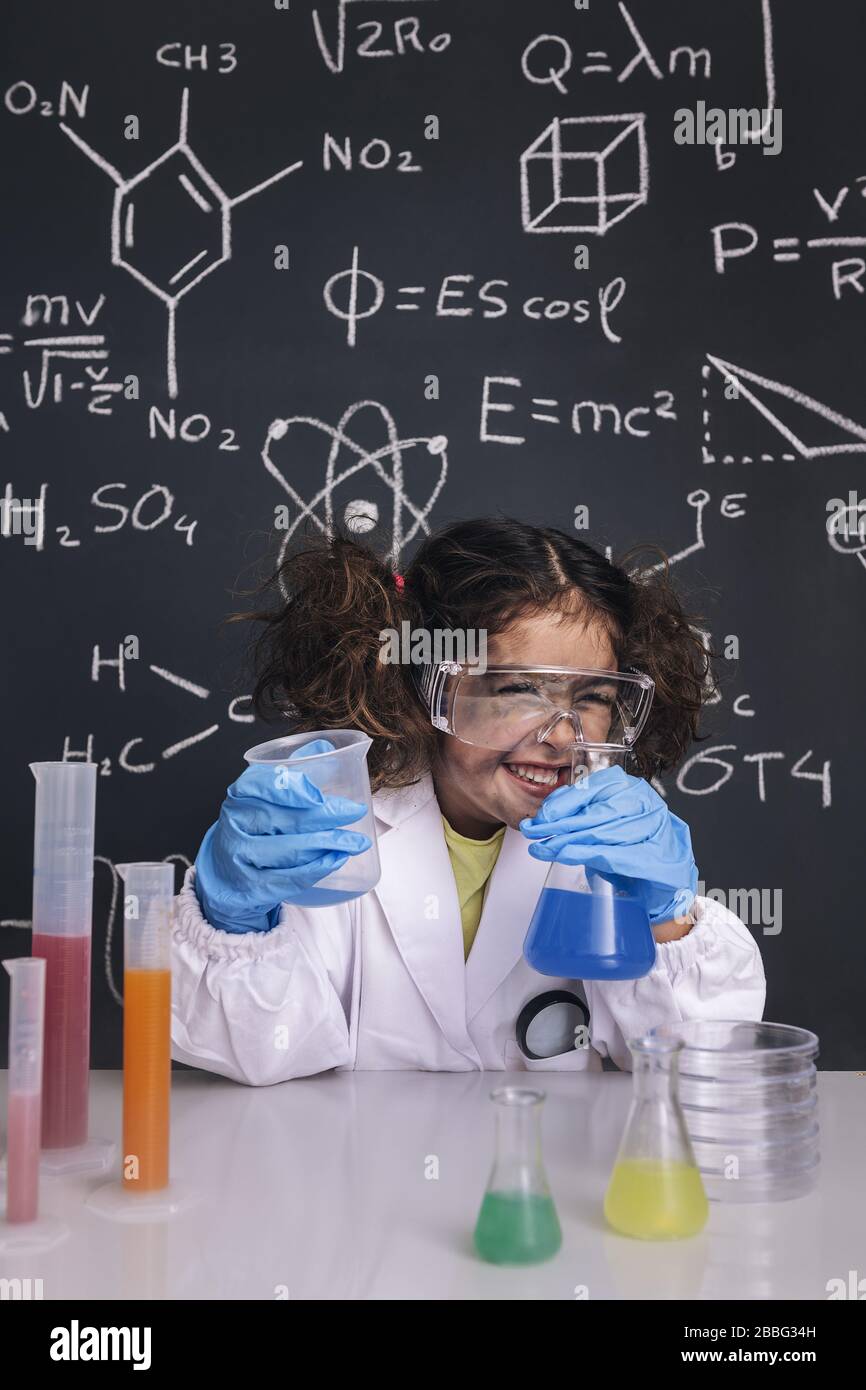 funny scientist girl with gloves and goggles in lab coat laughing