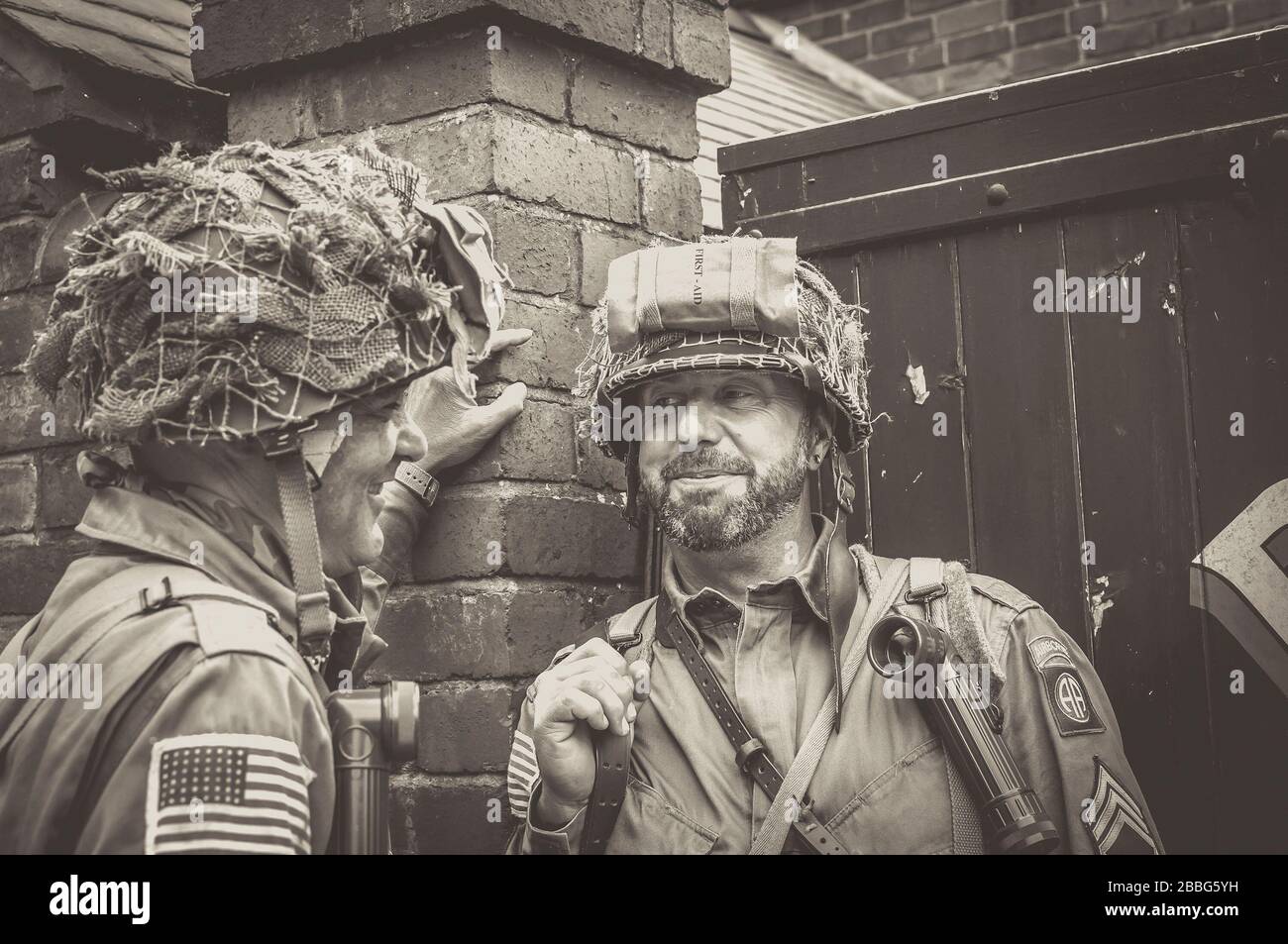 Friends smiling, young men chatting together in costume as American US military men soldiers, 1940's summer event, Black Country Living Museum, UK. Stock Photo