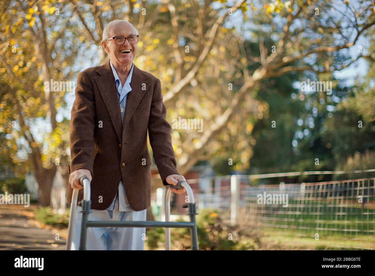 Laughing senior man having fun walking through a park with a walking frame. Stock Photo