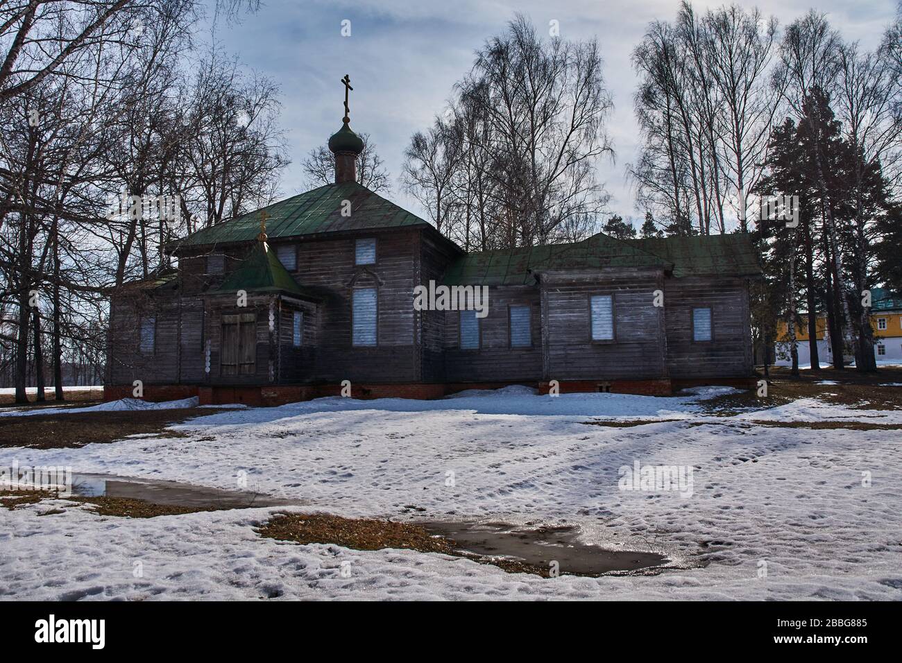 Ancient orthodox temple among trees. Landscape of central Russia. Windows, roof and doors are visible through branches. The village of Big Boldino Stock Photo