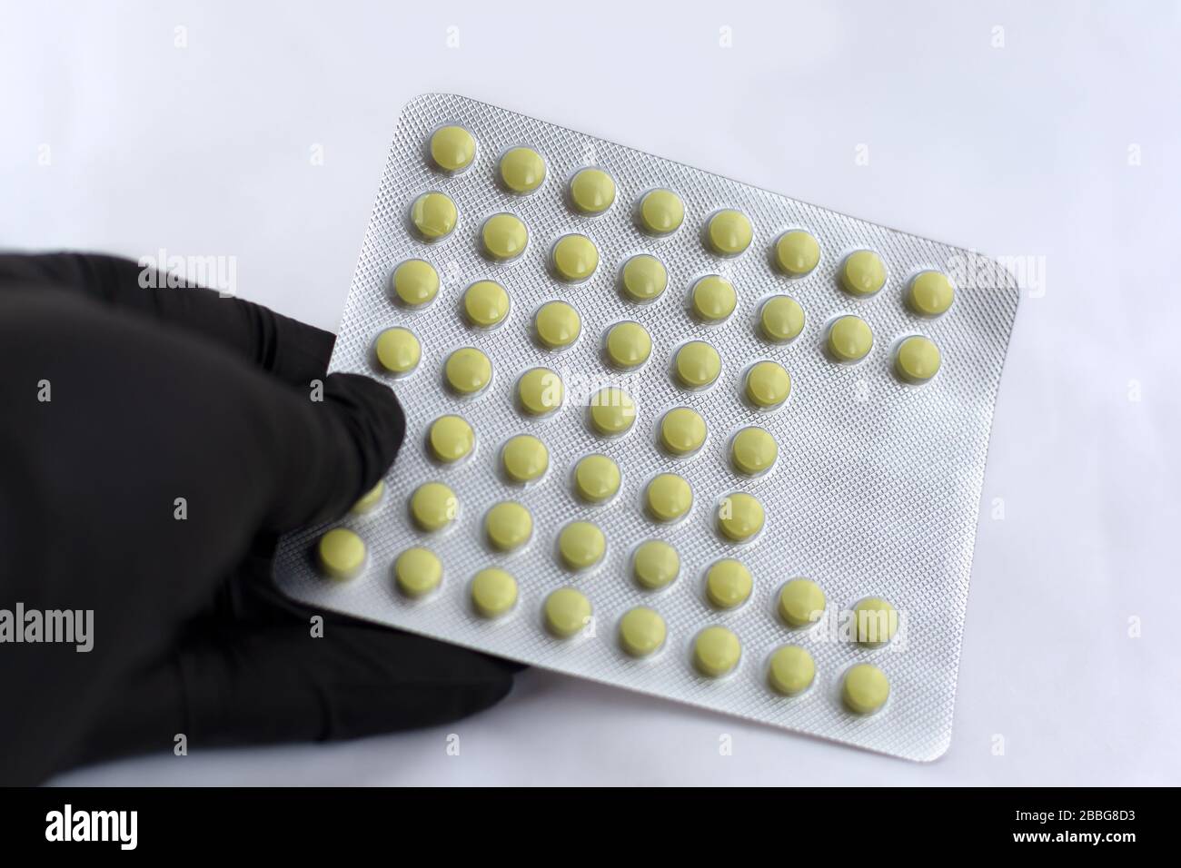 Pack of pills in hand in a black latex glove Stock Photo