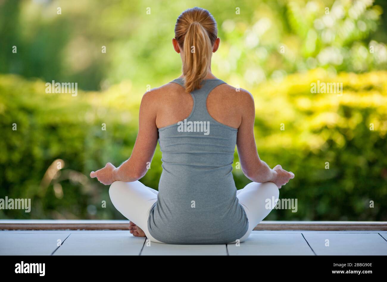 Rear view of a mid adult woman meditating on a deck Stock Photo - Alamy
