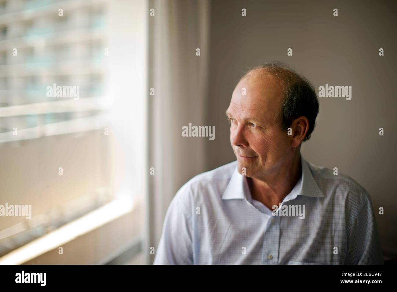 Mature man looking out the window of his office Stock Photo