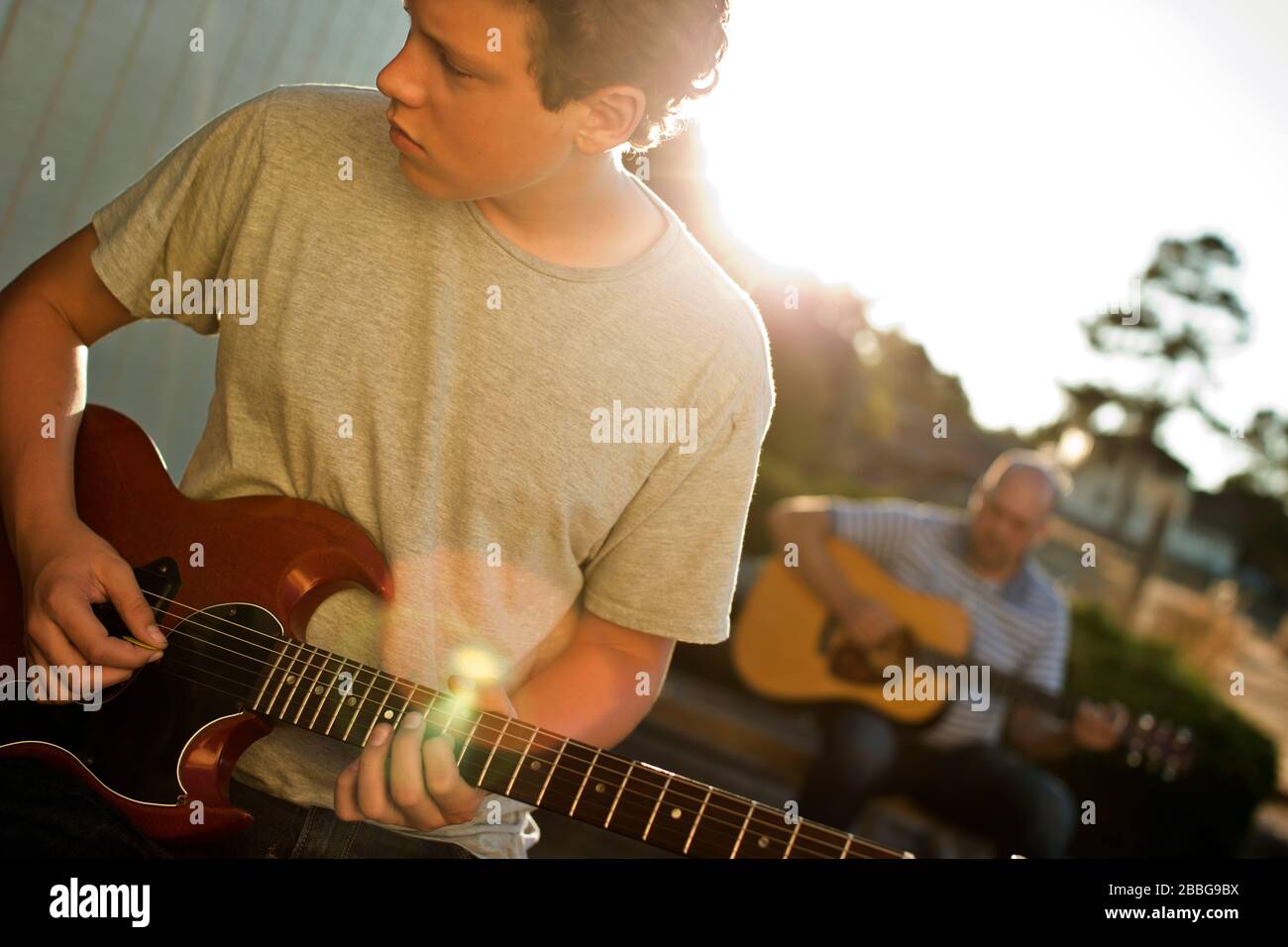 Father and son playing guitar together Stock Photo