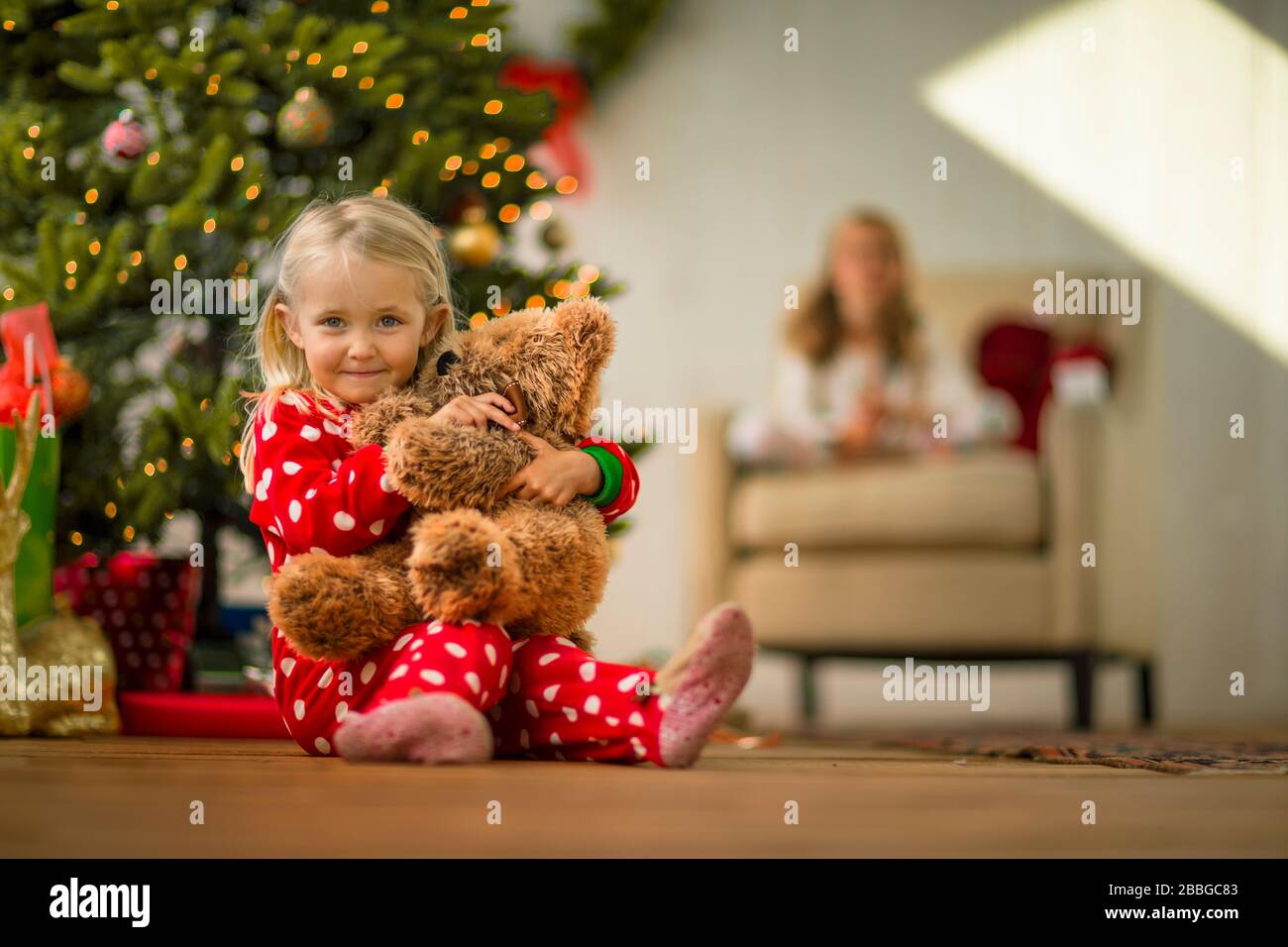 Portrait of a young girl hugging her teddy bear on Christmas morning ...