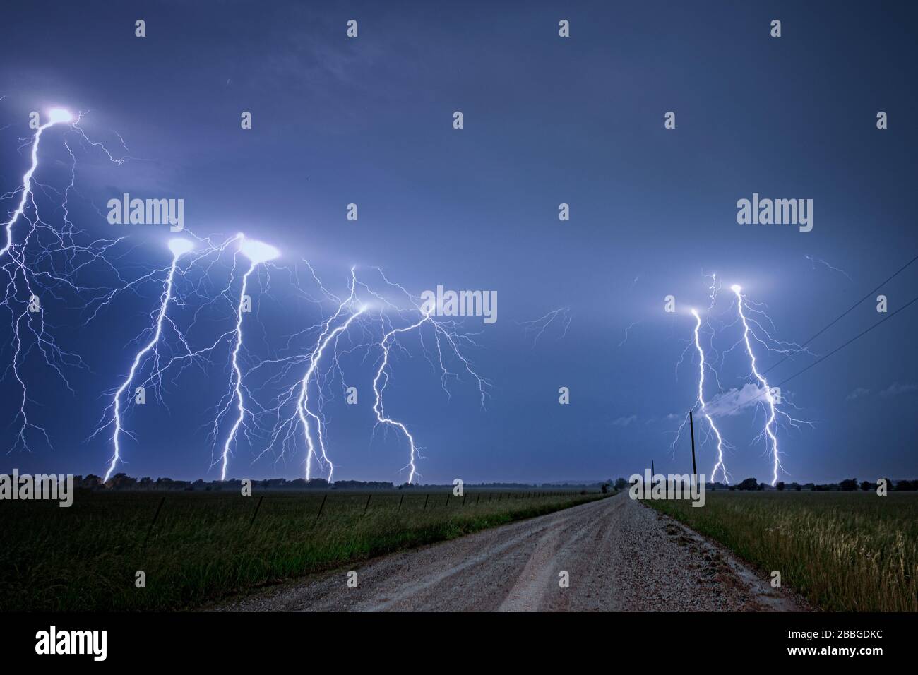 Storm with cloud to ground lightning flashing over old rural road in Kansas United States 4 image composition Stock Photo