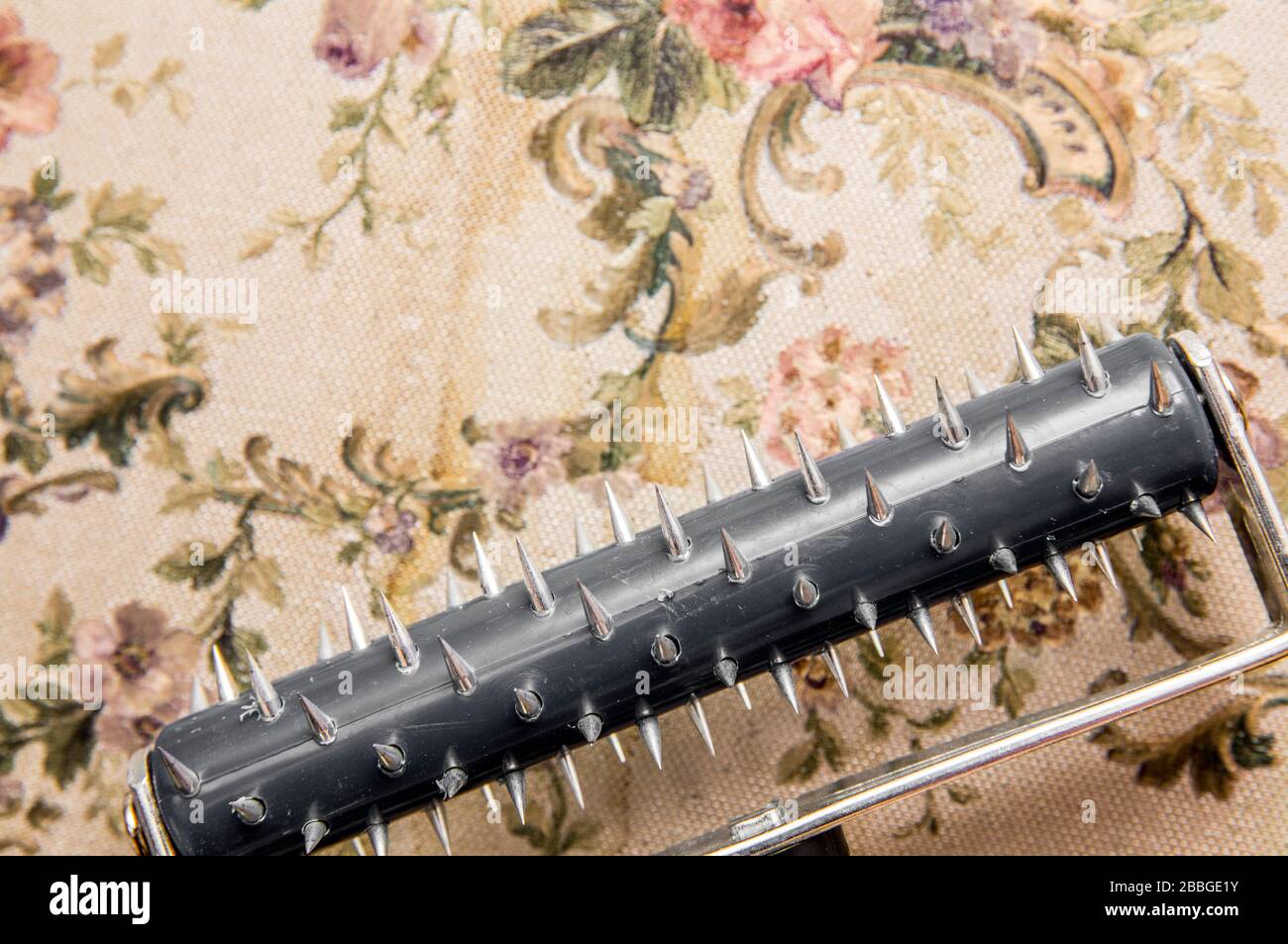 Removing old water damaged retro style wallpaper with rolling spike scoring  tool. After punching holes the removing liquid can absorb wallpaper for be  Stock Photo - Alamy