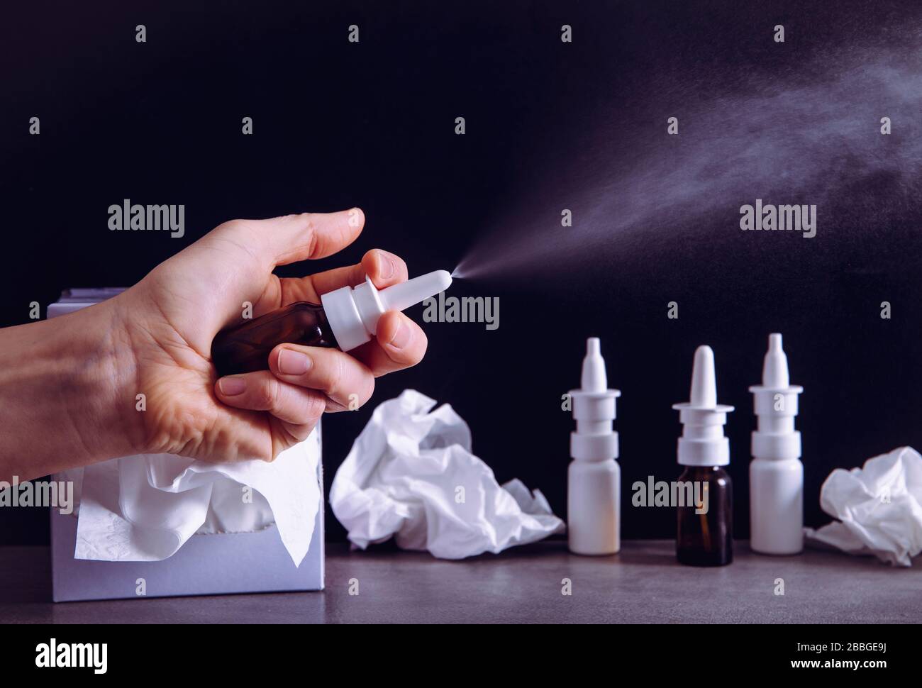 Woman hand using holding nose nasal spray treatment spray bottle and spraying. Fighting the flu and common cold concept. Lot of empty bottles. Stock Photo