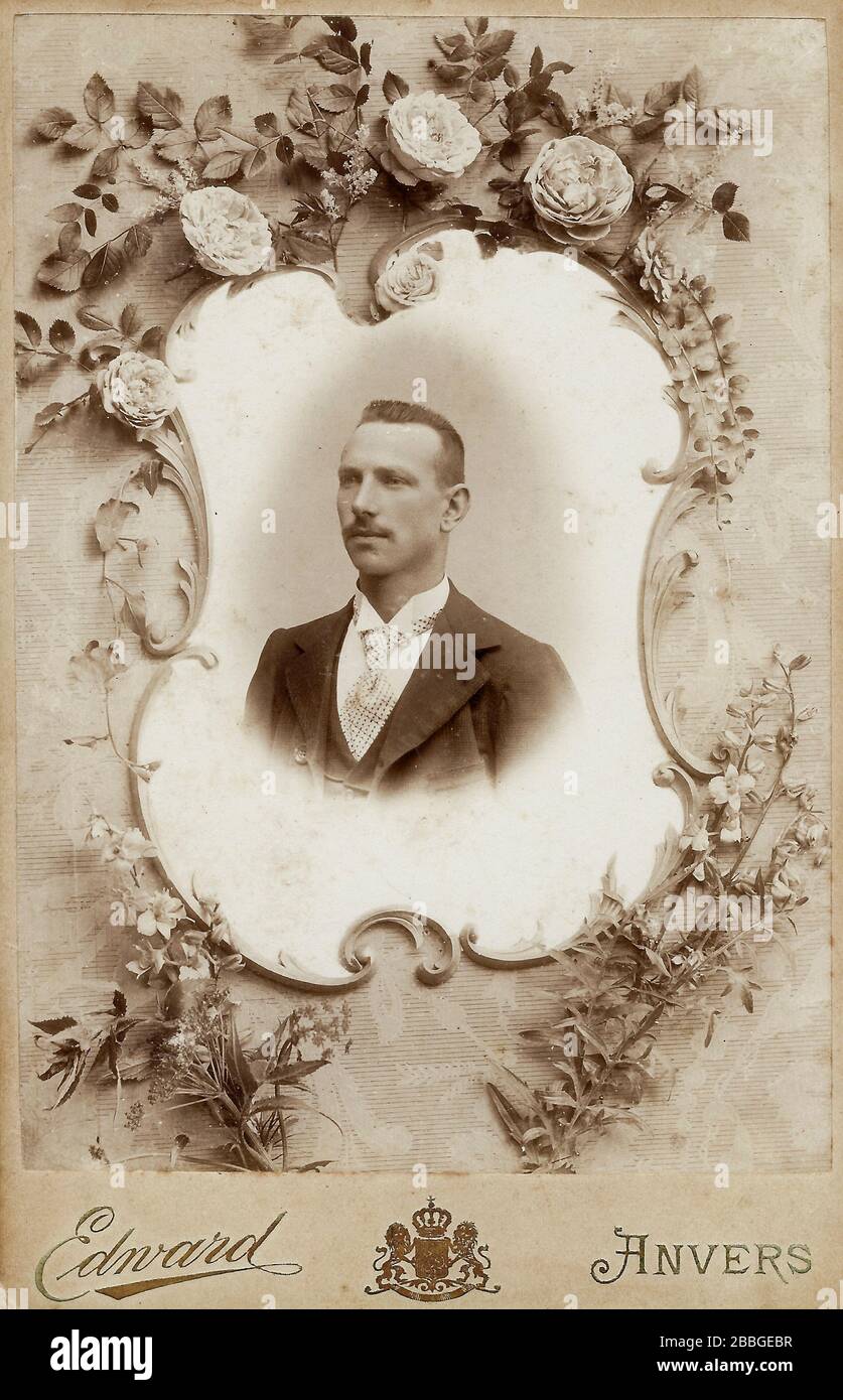 Very decorated cabinet card with a portrait of young man age 25-35, surrounded by flower decorations from around 1900, possibly mourning memorial card Stock Photo