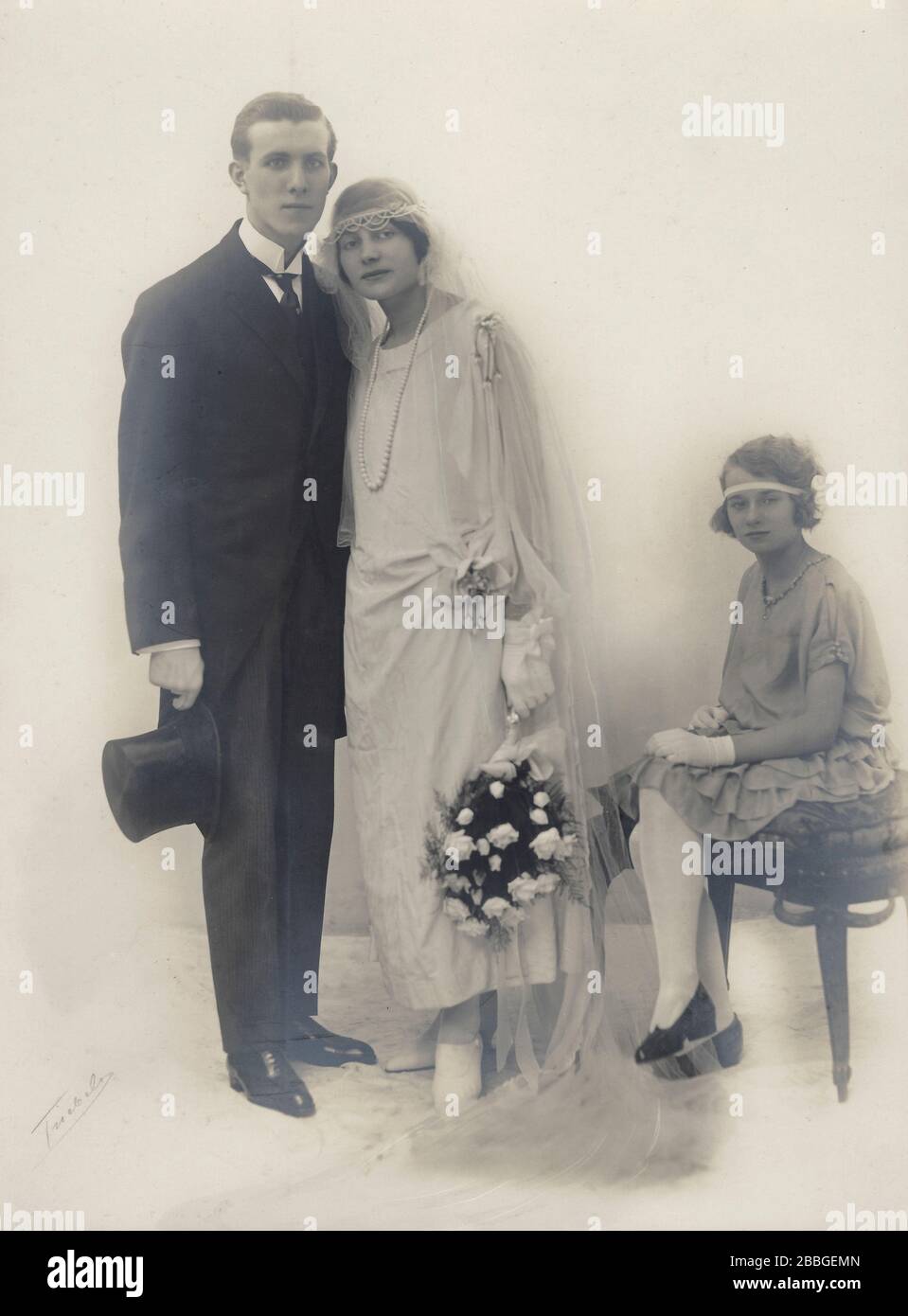 Studio wedding photograph of the marriage of a young couple around 1925 with the bridesmaid or a child from a previous marriage sitting next to them. Stock Photo